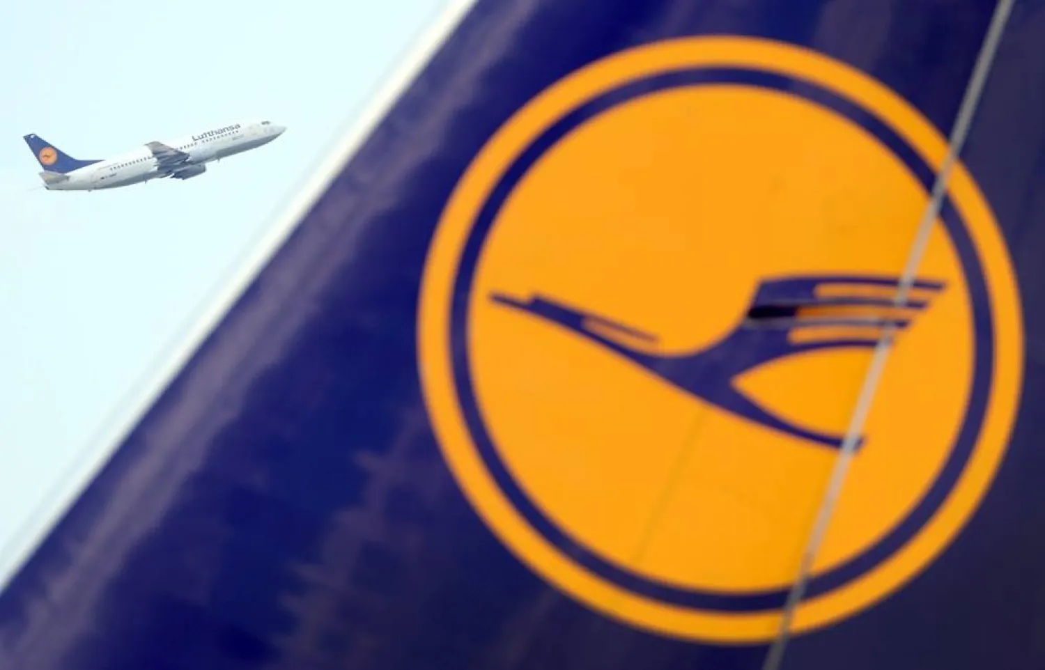 08 June 2013, Hesse, Frankfurt/Main: The Lufthansa logo can be seen on an airplane at Frankfurt am Main Airport, while another Lufthansa passenger plane takes off after take-off. (dpa)