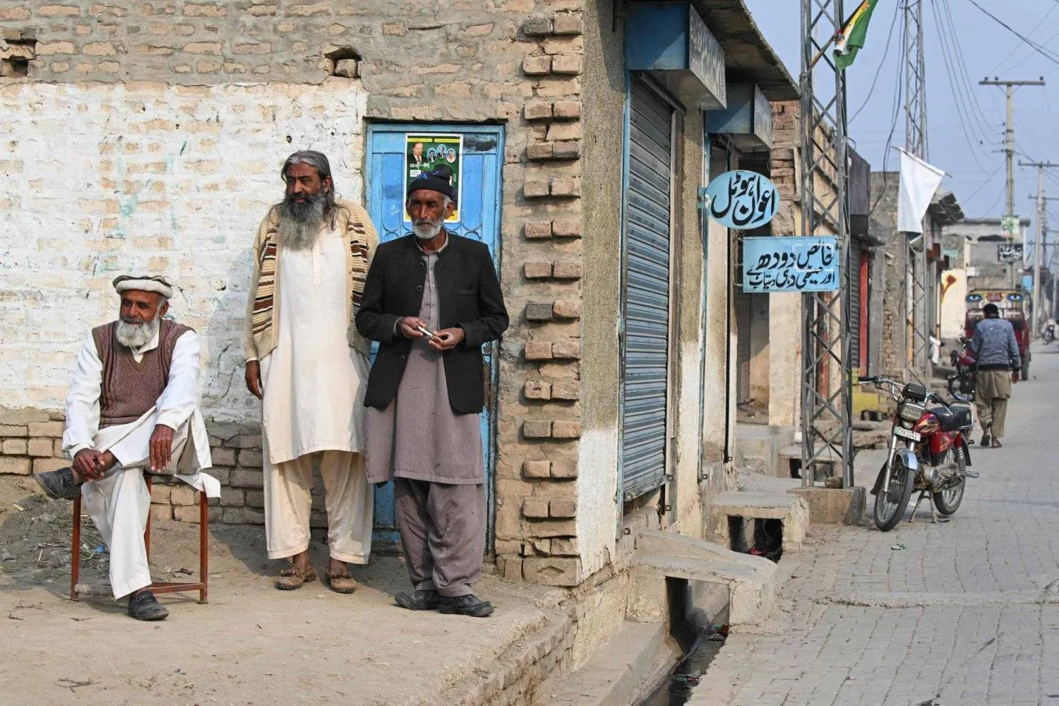 In this photograph taken on January 29, 2024, local men looks on as they stand along a street in Dhurnal of Punjab province, ahead of the upcoming general elections. (Photo by Farooq NAEEM / AFP)
