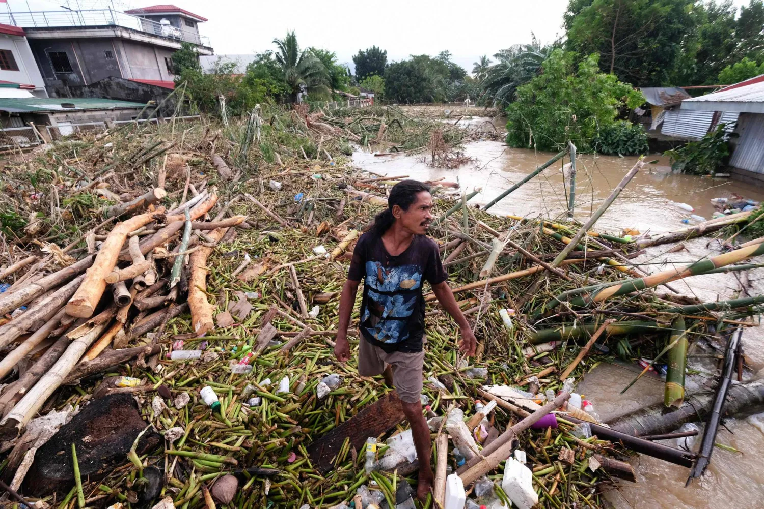A man walks along the debris from the floods brought about by Tropical Storm Trami in Nabua, Camarines Sur on October 25, 2024. (Photo by ZALRIAN SAYAT / AFP)