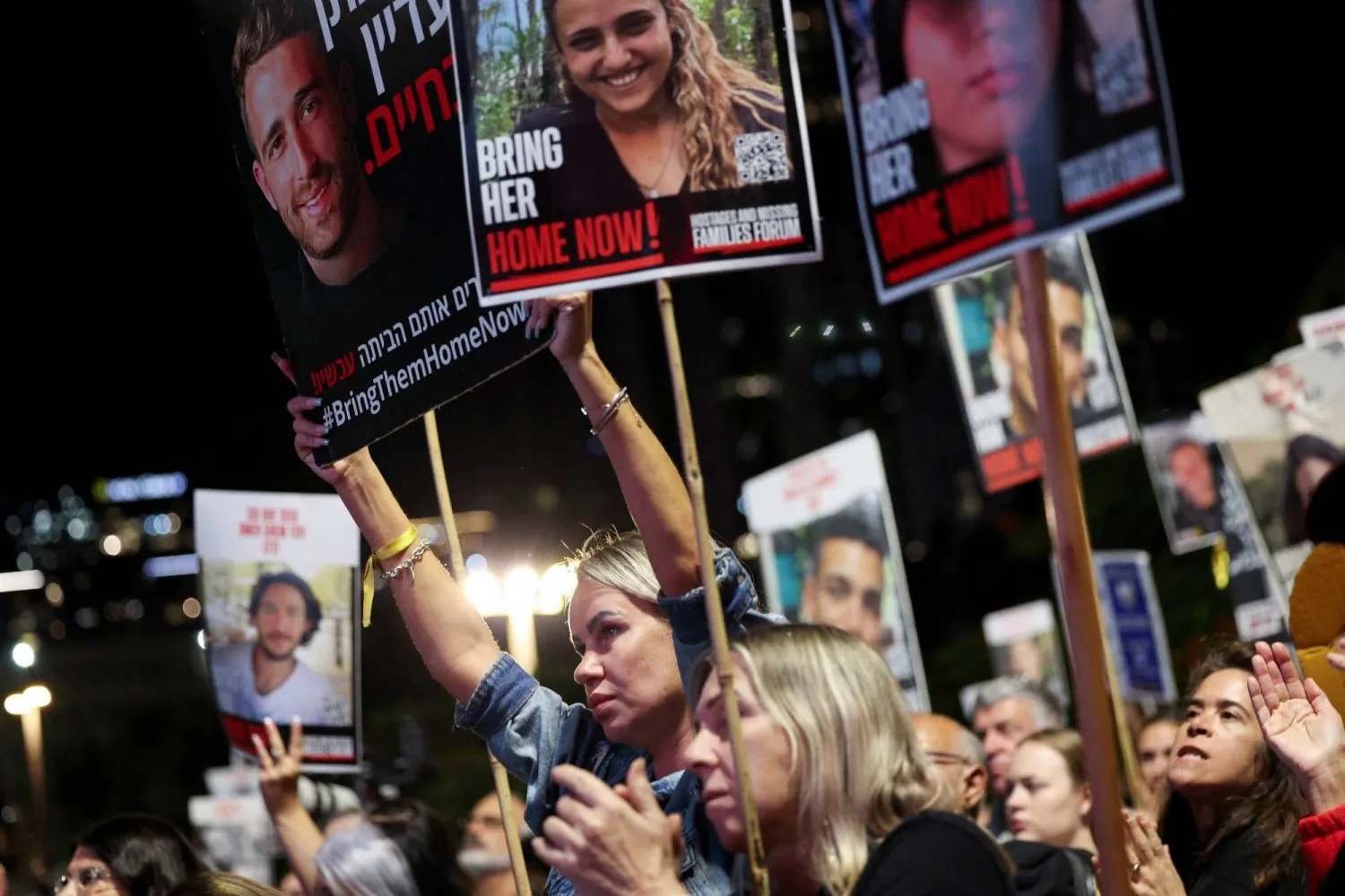 Tel Aviv'deki göstericiler, esirlerin fotoğraflarının yer aldığı pankartlar taşıyor. (Reuters)