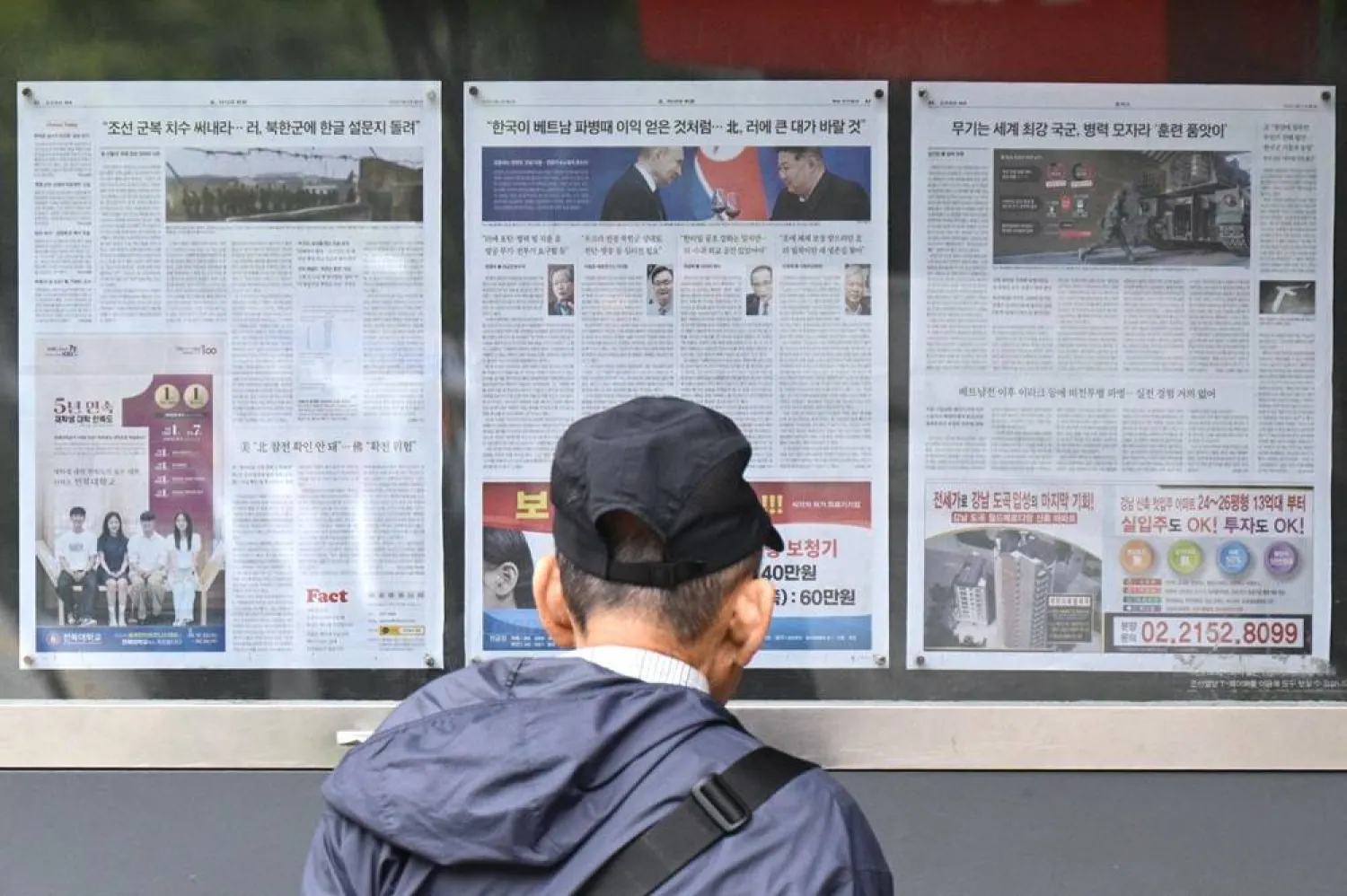 A man walks past a newspaper displayed on a street for the public in Seoul on October 21, 2024, with coverage on North Korea's decision to deploy thousands of soldiers to Ukraine's front lines and a photo (C) of North Korean leader Kim Jong Un and Russia's President Vladimir Putin toasting at a banquet in Pyongyang earlier this year. (AFP)