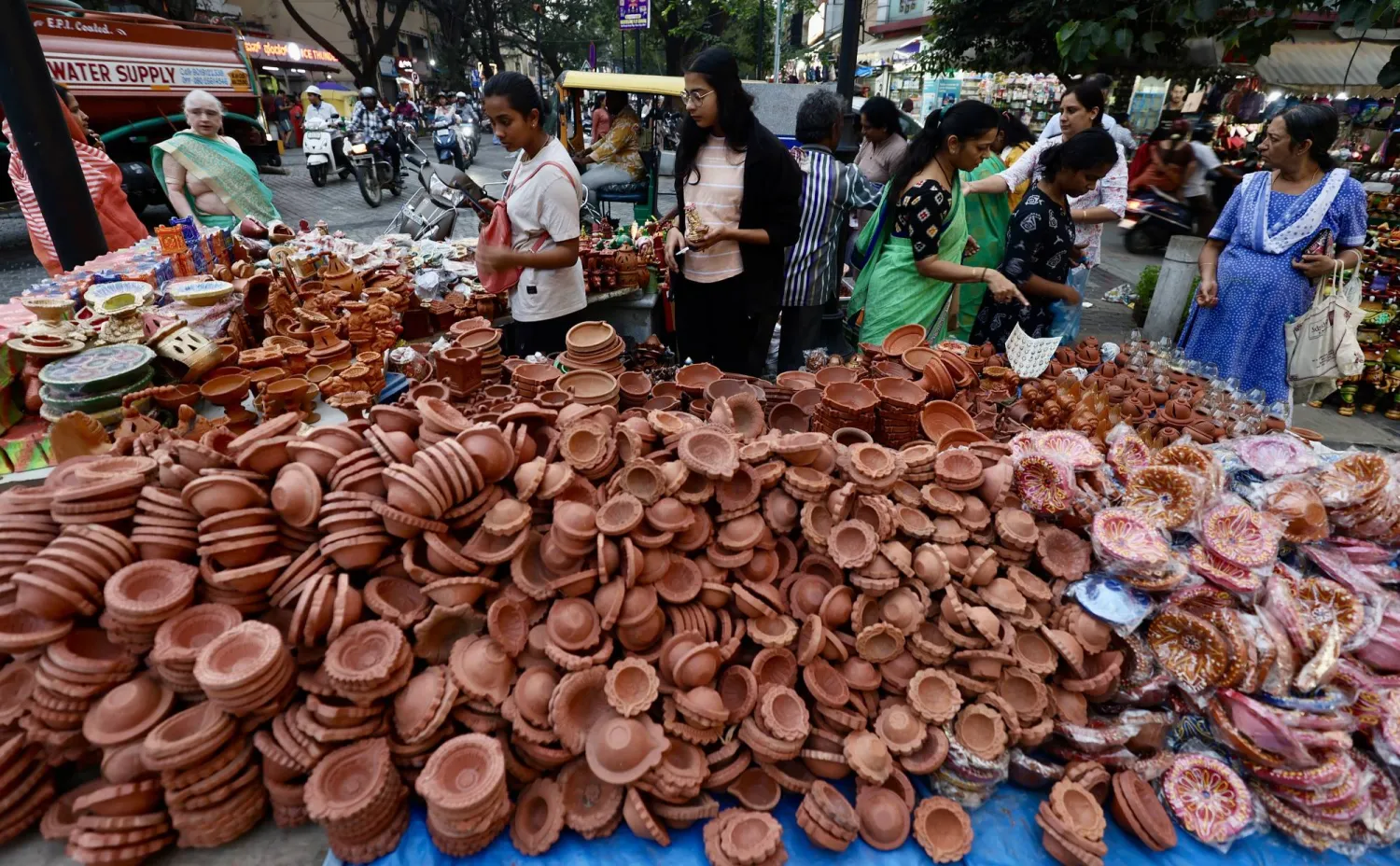ناس يزورون متاجر المصابيح الفخارية والزهور والأضواء الزخرفية قبل مهرجان ديوالي في بنغالور بالهند (إ.ب.أ)