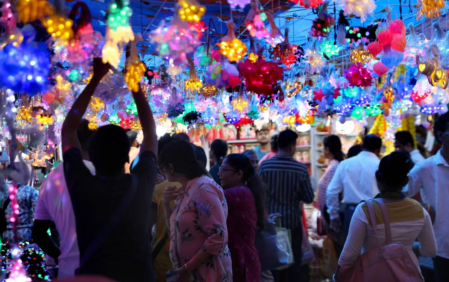 أشخاص يزورون متجراً مؤقتاً للأضواء الزخرفية قبل مهرجان ديوالي في كلكتا بالهند (إ.ب.أ)