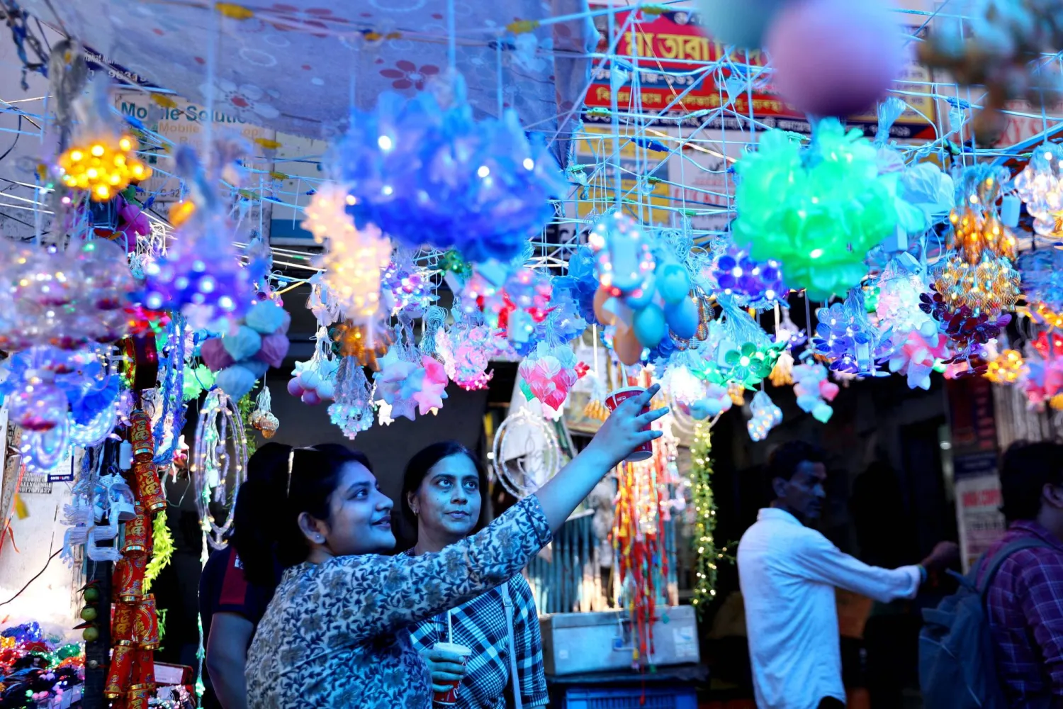 سكان يتجولون داخل متجر للأضواء الزخرفية قبل مهرجان ديوالي في الهند (إ.ب.أ)
