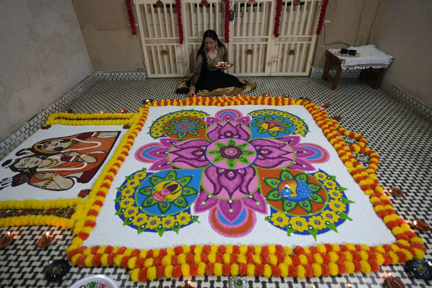 فتاة تضع مصباحاً فخارياً بجوار رانغولي وهو نمط مزخرف يدوياً على الأرض كجزء من احتفالات ديوالي في أحمد آباد (أ.ب)