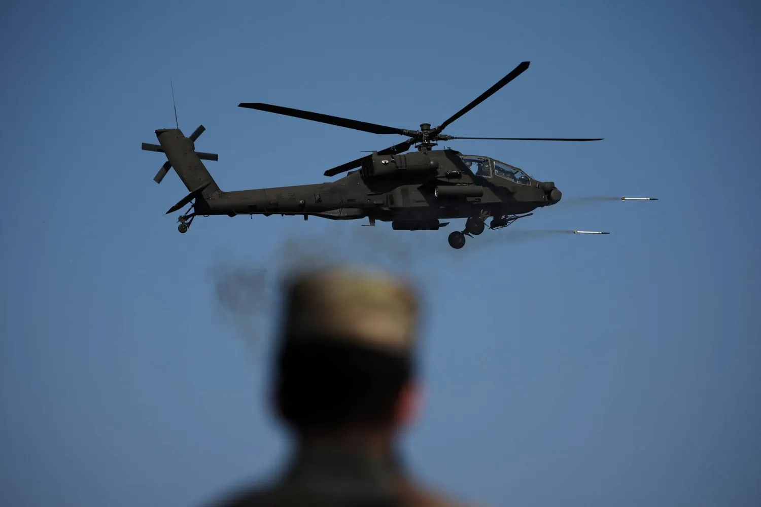 A US soldier looks on at an AH-64E Apache helicopter of the South Korean army firing missiles during a combined live fire drill between South Korea and US army at the Rodriguez Live Fire Complex, in Pocheon South Korea, October 30, 2024. REUTERS/Kim Hong-Ji