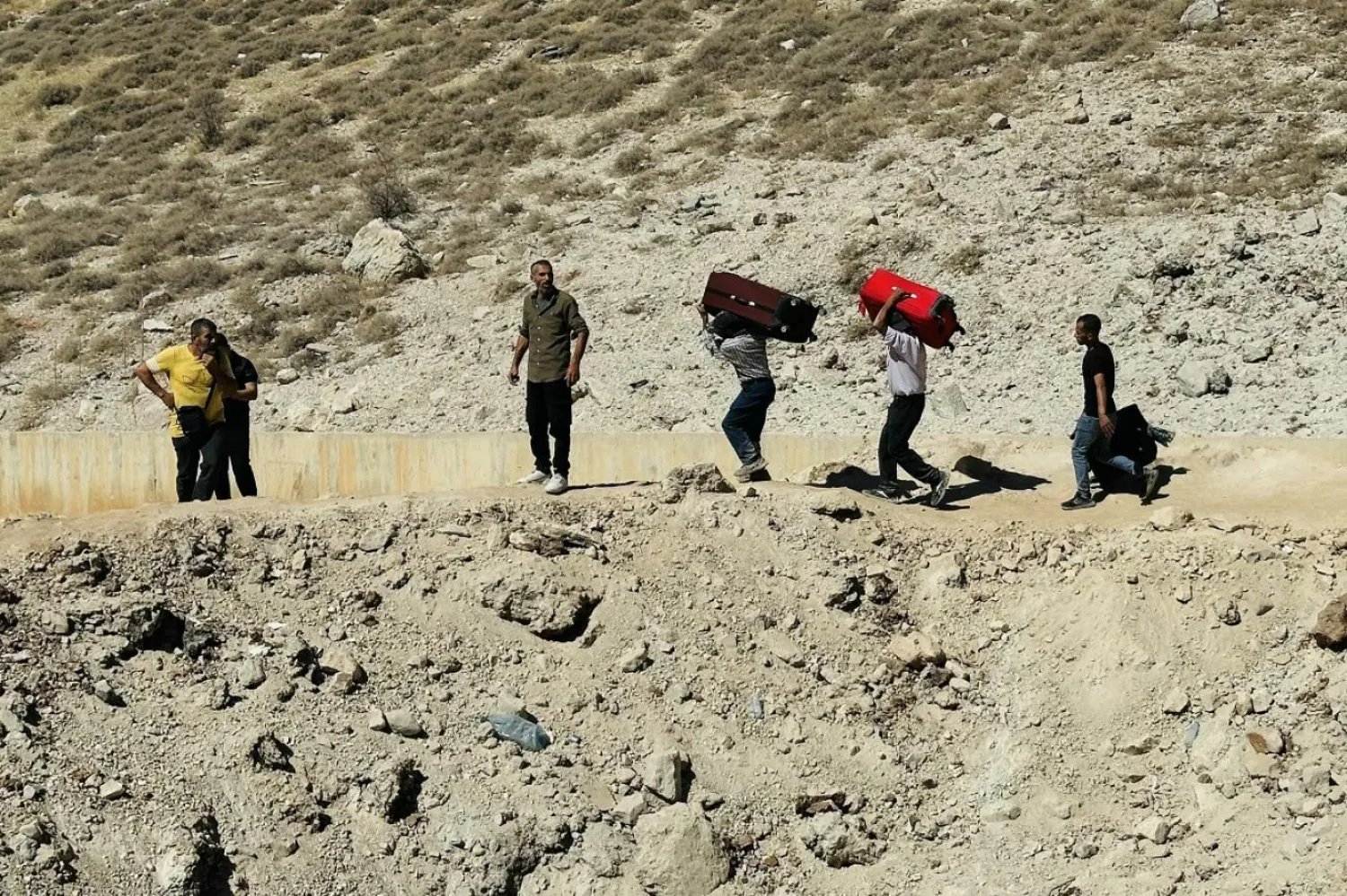 Bir köyde, köy sakinlerinin ayrılmalarını istemesi üzerine burayı terk eden onlarca yerinden edilmiş kişi (AFP)