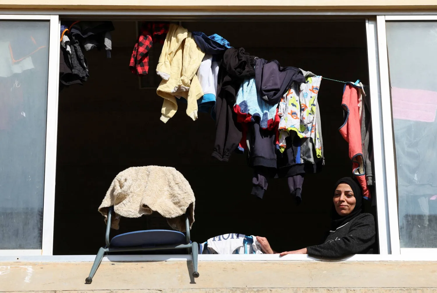 A displaced woman looks out from a window at a school turned into a shelter housing displaced people who fled from Baalbek and surrounding areas, in the mountainous Christian town of Deir al-Ahmar in eastern Lebanon October 31, 2024. REUTERS/Mohamed Azakir
