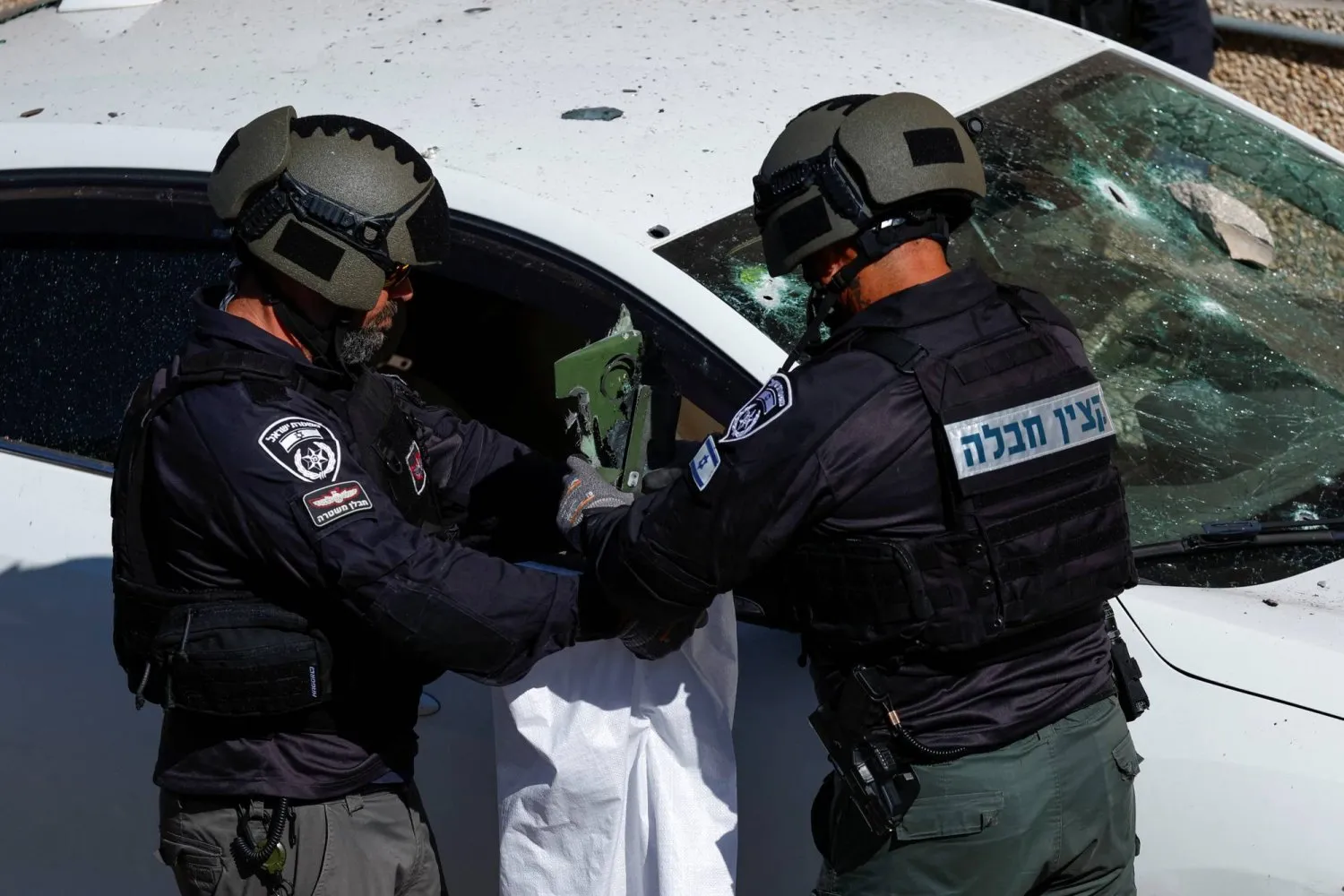 İsrail güvenlik güçleri, bir insansız hava aracı saldırısının gerçekleştiği yerde tahrip edilmiş araçtan delil topluyor. (Reuters)