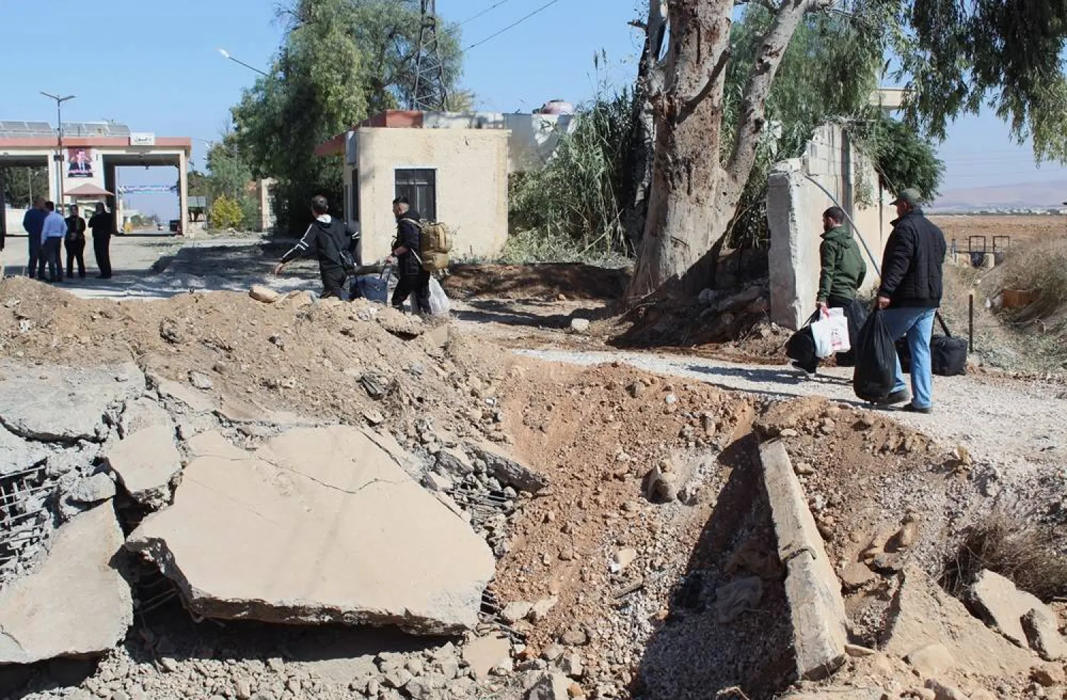  People carry their belongings while crossing from Lebanon into Syria, as they walk past a crater caused in the aftermath of an Israeli strike that occurred early on Friday morning, at Jousieh crossing between Syria and Lebanon, Syria October 28, 2024. (Reuters)