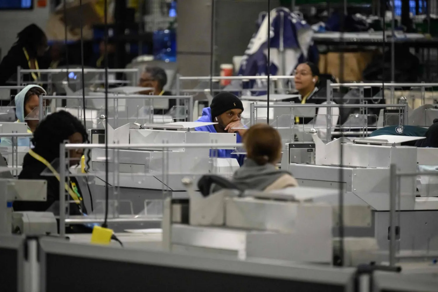 موظفو مجلس انتخابات مقاطعة فيلادلفيا يجلسون أمام الآلات أثناء انتظارهم وصول بطاقات الاقتراع إلى مركز فرز الأصوات الانتخابية (أ.ف.ب)