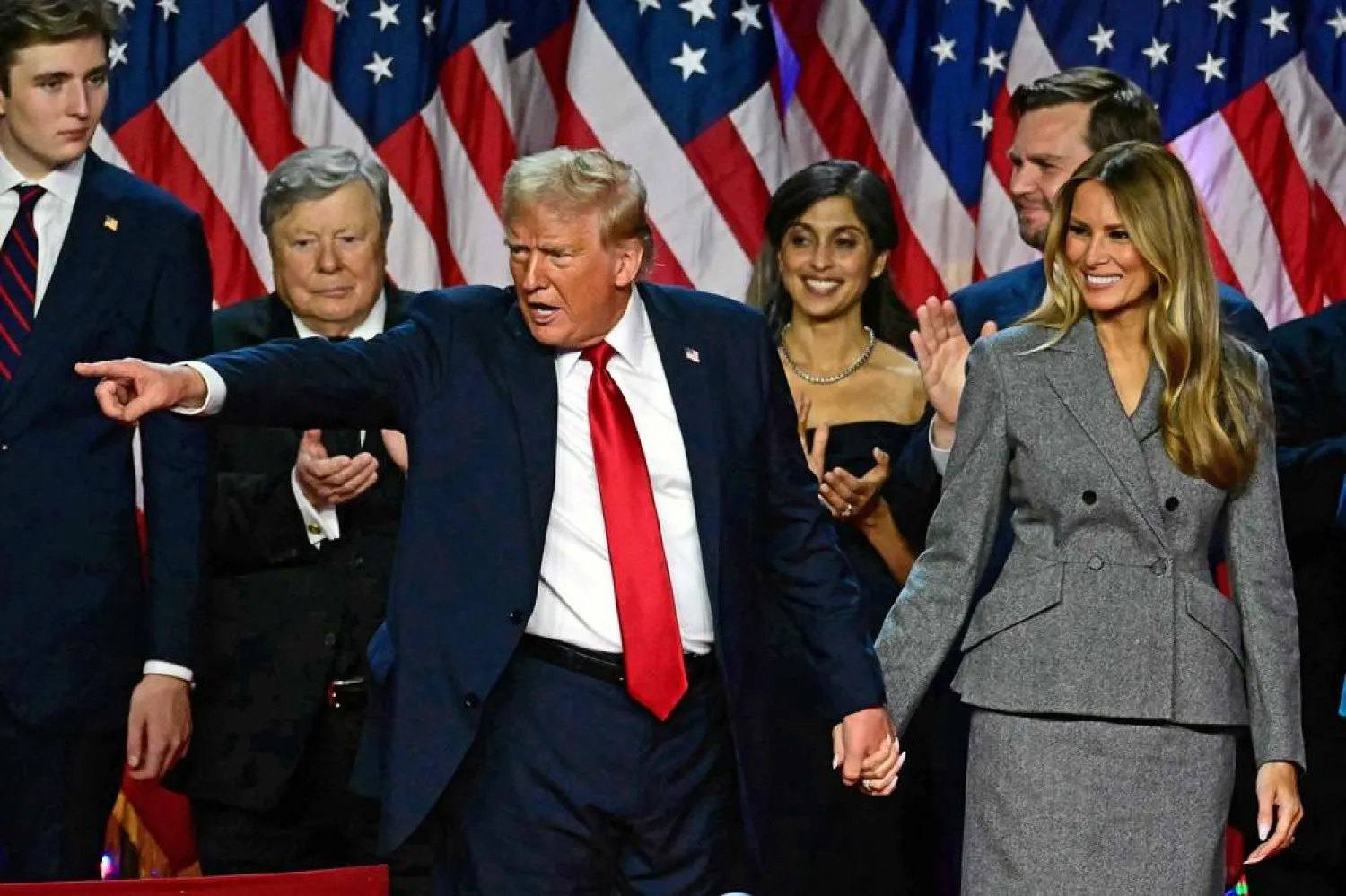 Former US President and Republican presidential candidate Donald Trump gestures at supporters after speaking as he holds hands with former US First Lady Melania Trump during an election night event at the West Palm Beach Convention Center in West Palm Beach, Florida, early on November 6, 2024. (AFP)