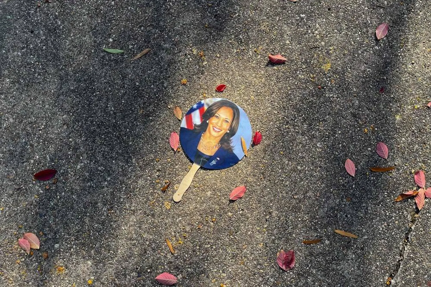 A hand fan depicting US Vice President Kamala Harris lays on a sidewalk in Washington, DC, on November 6, 2024. (AFP) 