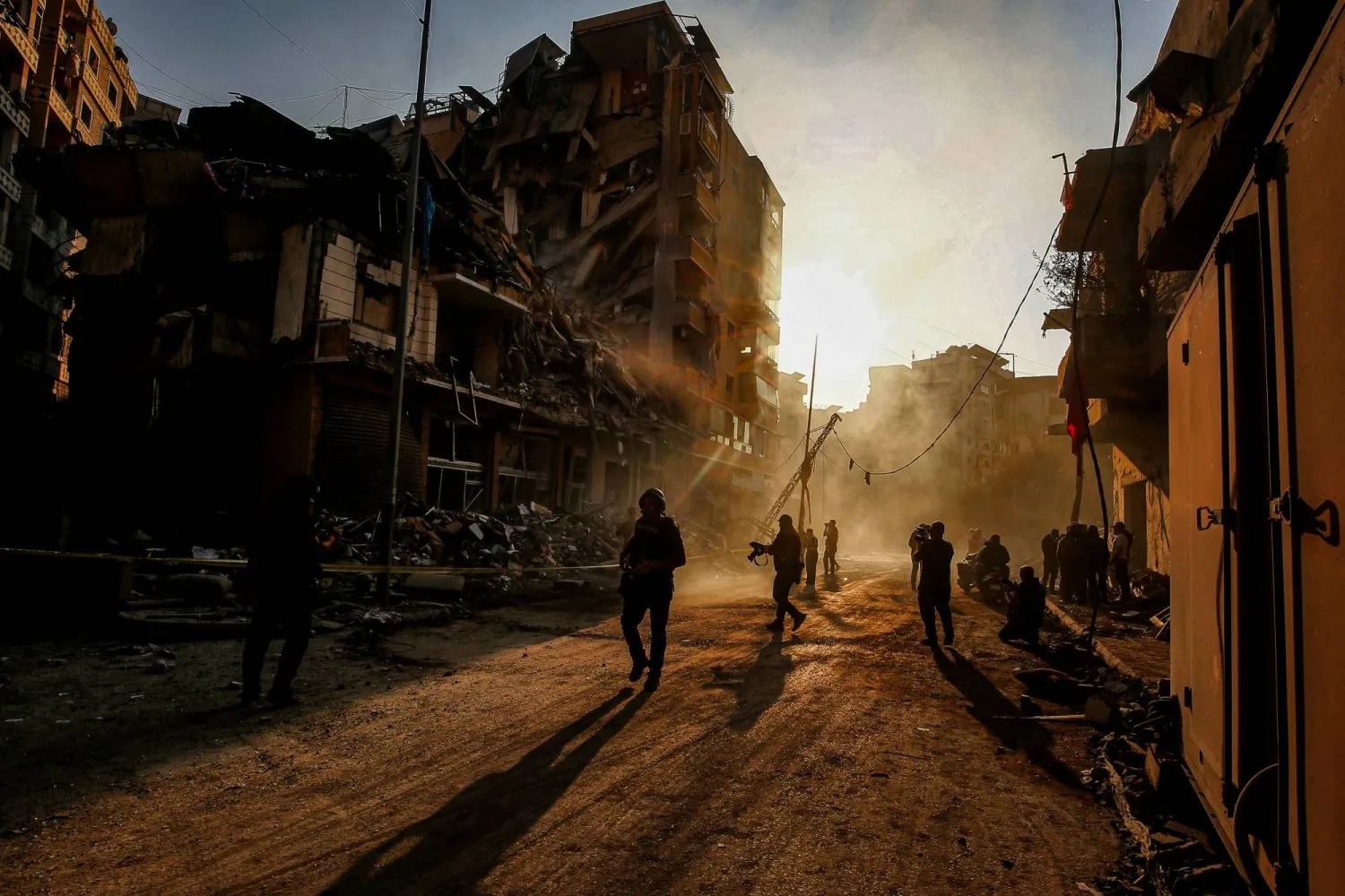 İsrail'in Beyrut'un güney banliyölerine düzenlediği saldırılarda yıkılan binaların arasında yürüyen gazeteciler (DPA)