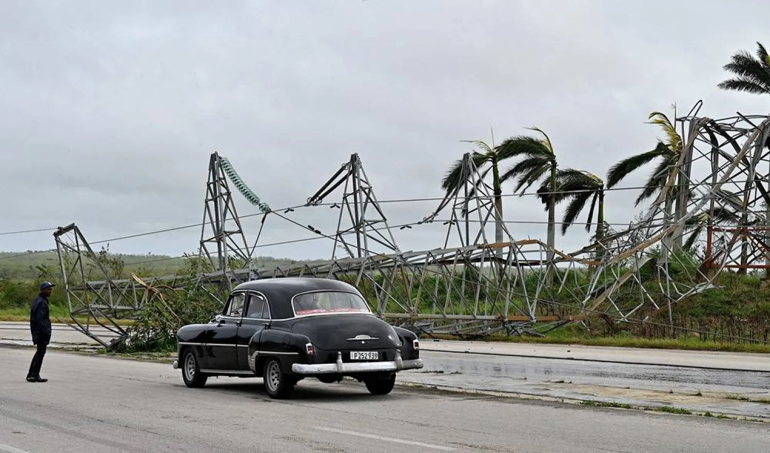 A car drives past a high tension electric tower knocked down during the passage of Hurricane Rafael on the road linking Artemisa with Havana, on November 7, 2024. (AFP)