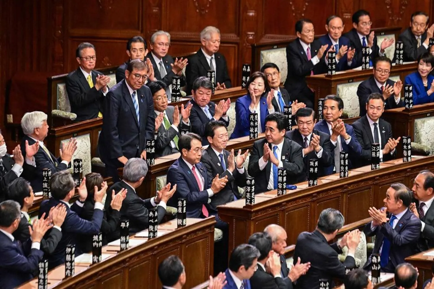 Lawmakers applaud as Japan's Prime Minister Shigeru Ishiba (standing L) is reappointed as leader after the second round of a parliamentary vote to nominate a prime minister following the October 27 general election, during a special session of parliament in Tokyo on November 11, 2024. (AFP)