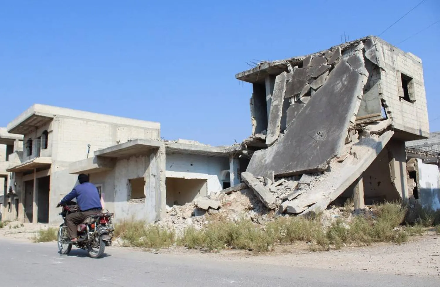 A man rides a motorbike past a damaged building in Homs, Syria November 7, 2024. (Reuters)