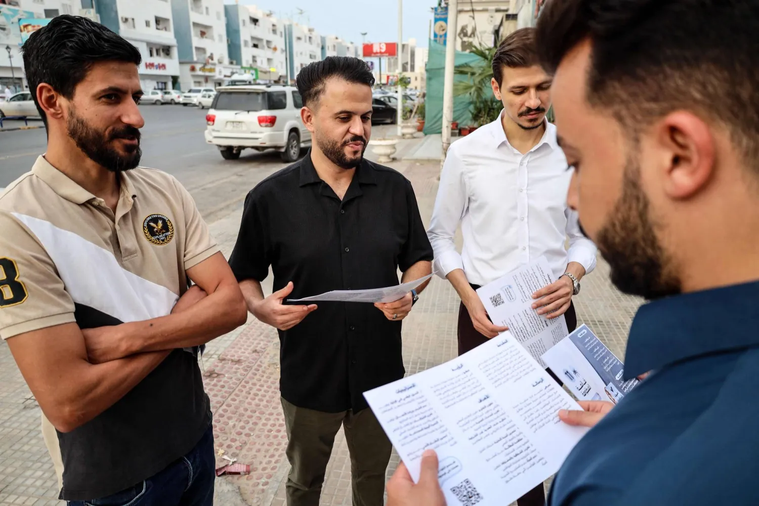 ليبيون من مصراته يتفحصون منشورات تحث على المشاركة بكثافة في الانتخابات (أ.ف.ب)