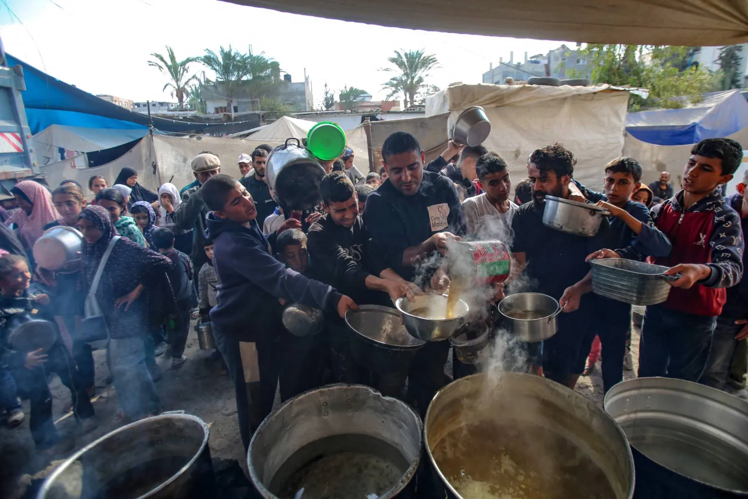 نازحون يتجمعون لتلقي وجبة ساخنة في مخيم البريج للاجئين في وسط قطاع غزة السبت (أ.ف.ب)