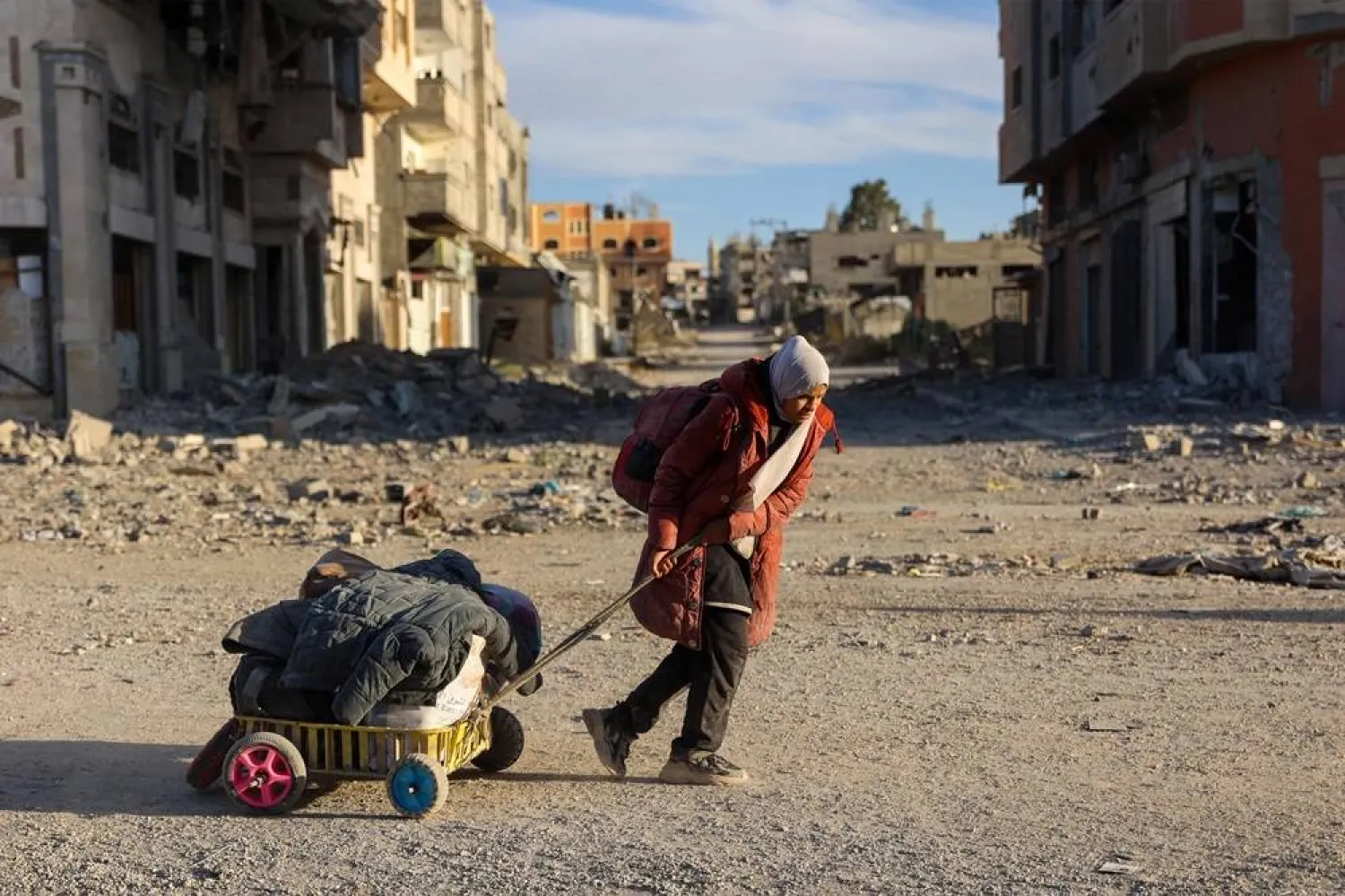 A displaced Palestinian woman carries her belongings as she flees Beit Lahia in the northern Gaza Strip walk on the main Salah al-Din road on November 17, 2024, amid the ongoing war between Israel and Hamas. (AFP) 