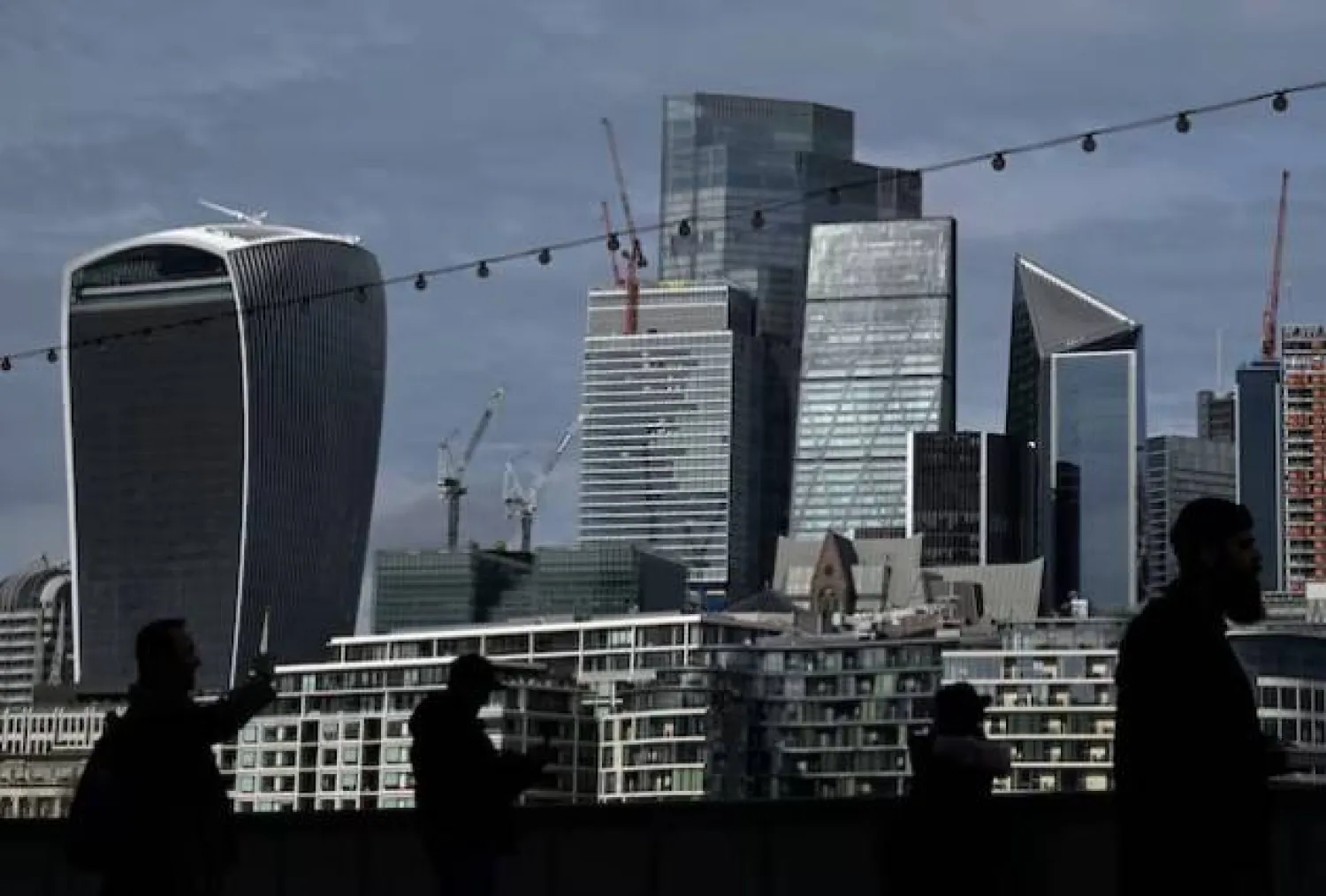 يتجول الناس بالحي المالي بلندن مع ناطحات السحاب في الخلفية (رويترز)
