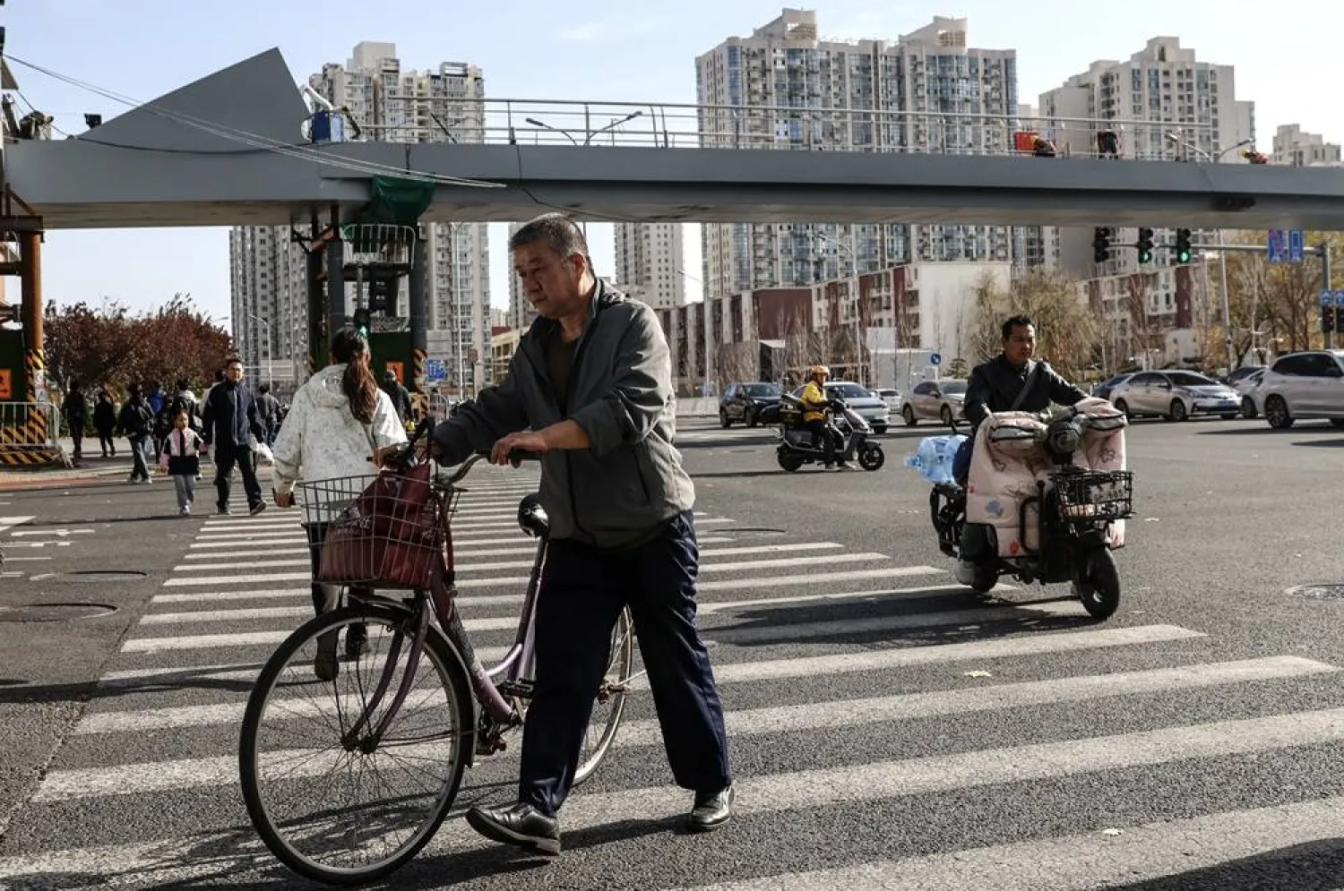 A man walks with his bicycle along a crosswalk in Beijing, China, 16 November 2024. (EPA)