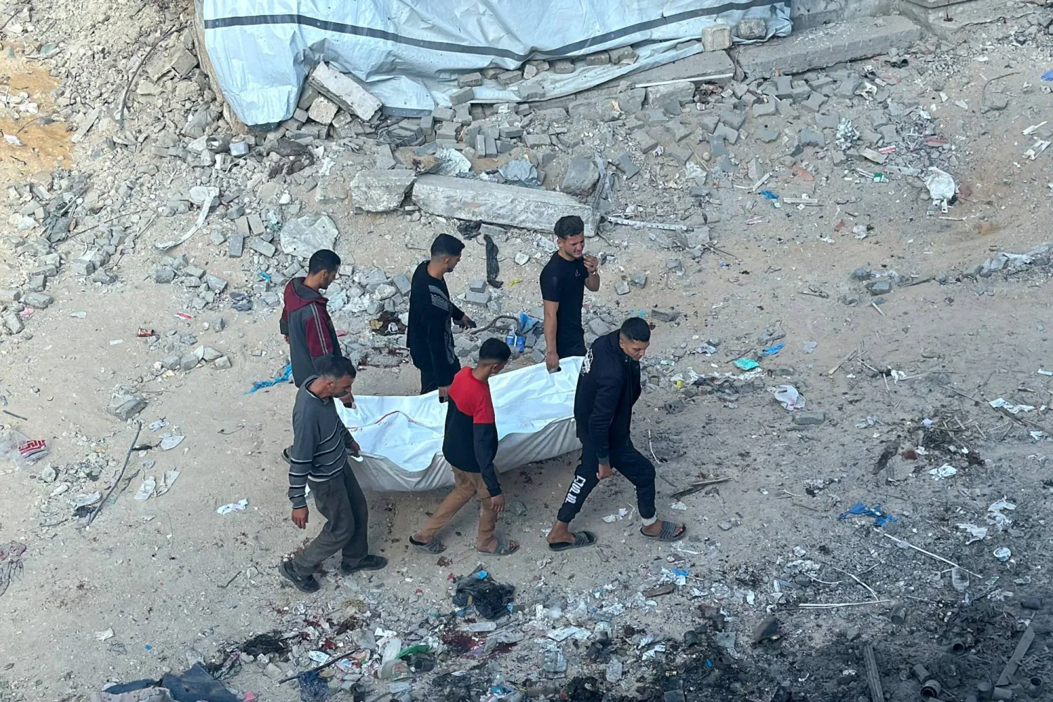 فلسطينيون يحملون جثة رجل قتل في غارة إسرائيلية على بيت لاهيا شمال قطاع غزة (أ.ف.ب)