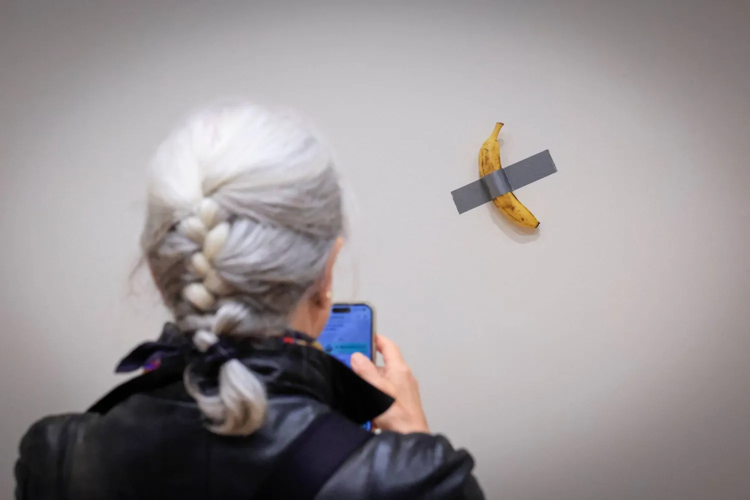 (FILES) A journalist takes a picture of Italian visual artist Maurizio Cattelan's duct-taped Banana entitled "Comedian," displayed during a media preview at Sotheby's in New York, on November 8, 2024. (Photo by kena betancur / AFP) 