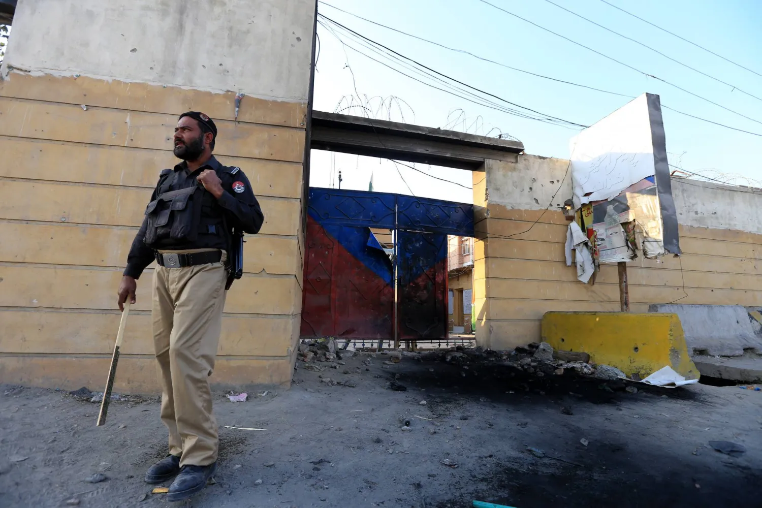شرطي باكستاني يقف خارج مركز تعرّض لأضرار جزئية بسبب احتجاجات (إ.ب.أ)