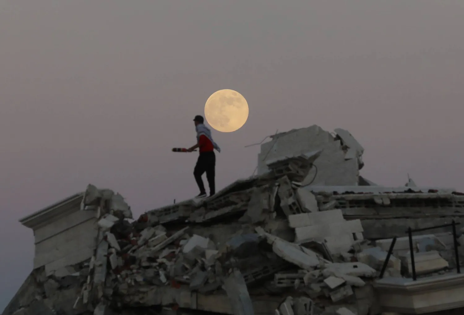 القمر المكتمل يرتفع فوق المباني المدمرة في منطقة الزوايدة في وسط قطاع غزة (د.ب.أ)