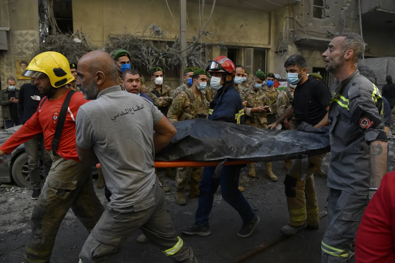 رجال الإنقاذ يحملون جثة على نقالة أثناء بحثهم عن مفقودين تحت أنقاض مبنى مدمر بعد أن أصابت الغارات الجوية الإسرائيلية منطقة سكنية في حي البسطة بوسط بيروت (إ.ب.أ)