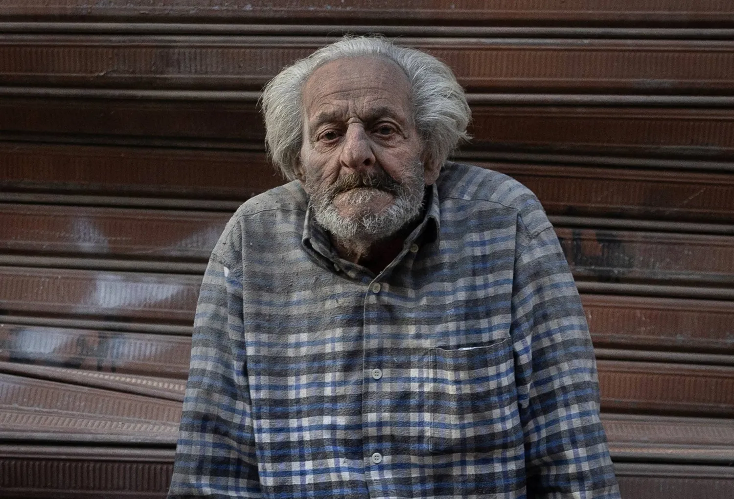 رجل مغطى بالأتربة يجلس بالقرب من حي البسطة في قلب بيروت إثر غارة إسرائيلية (رويترز)