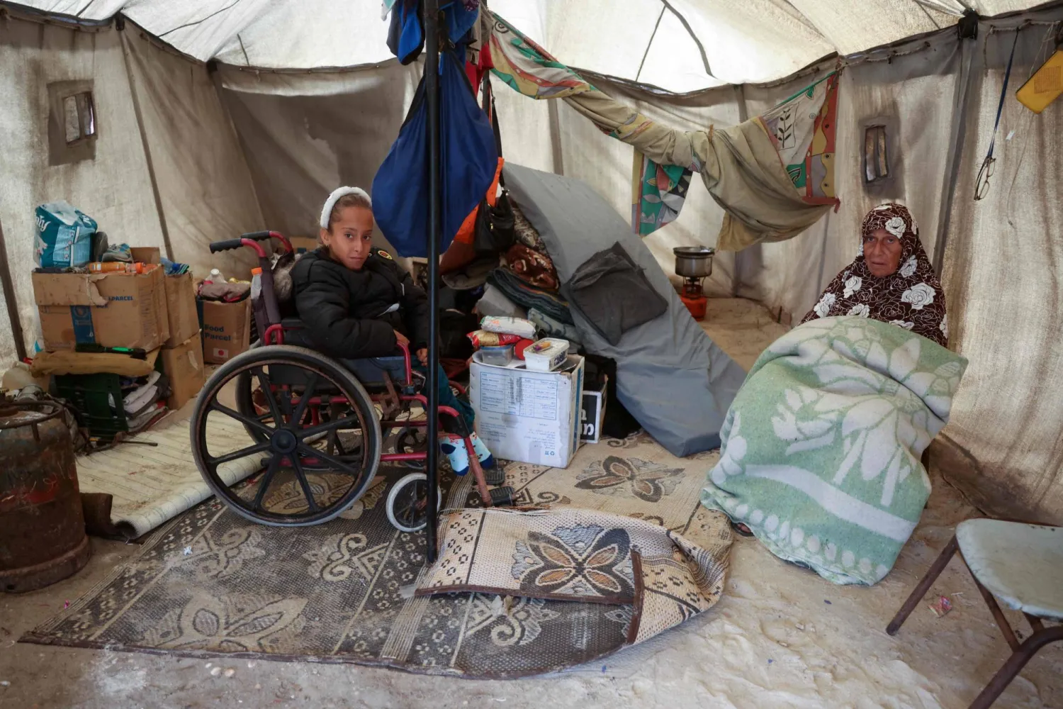 عائلة نازحة داخل خيمة ضعيفة تحميهم من برد الشتاء (أ.ف.ب)