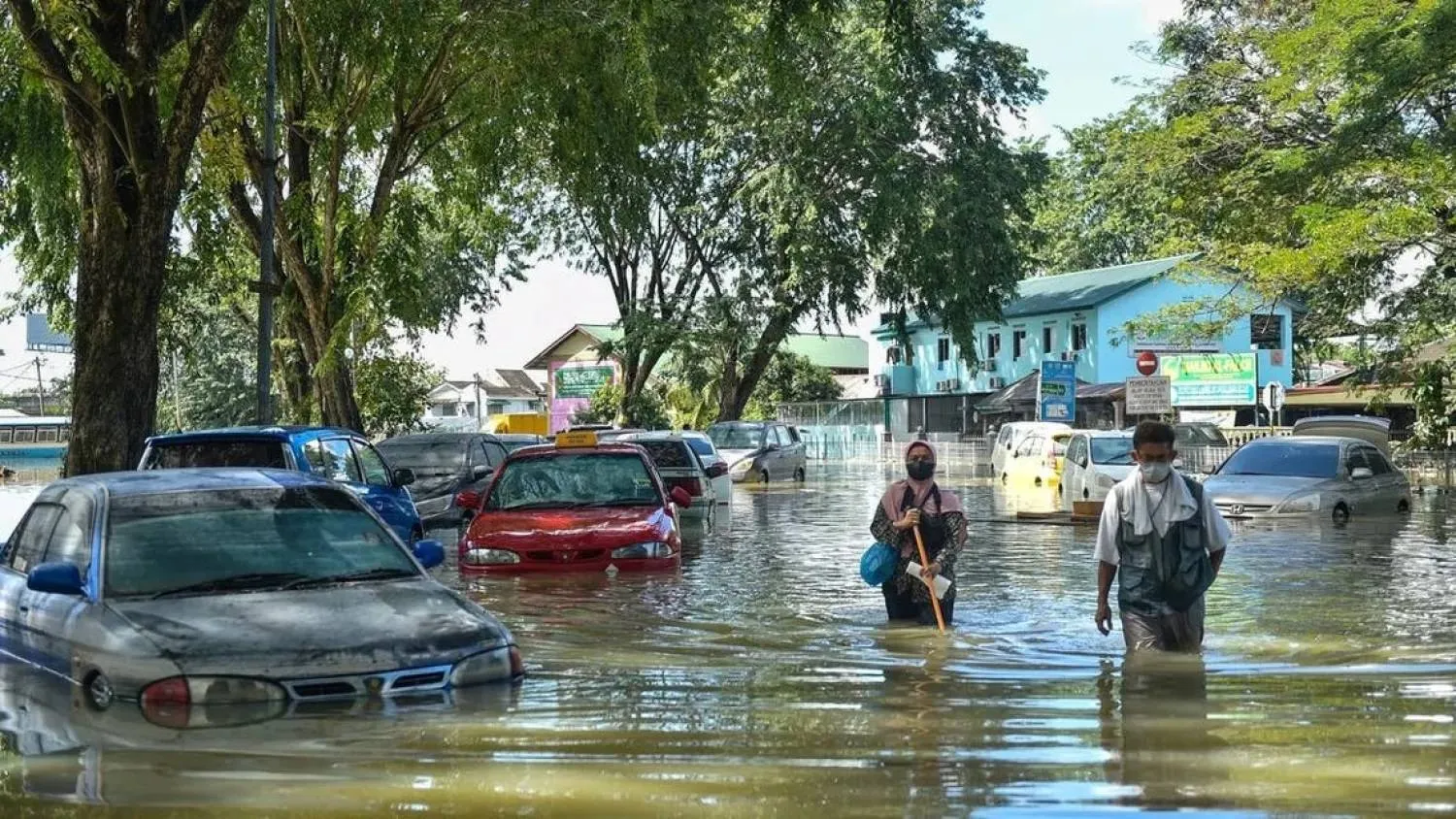 File photo: People walk past cars partially submerged in floodwaters in Shah Alam, Selangor on December 21, 2021, as Malaysia faces massive floods that have left at least 14 dead and more than 70,000 displaced. (AFP)