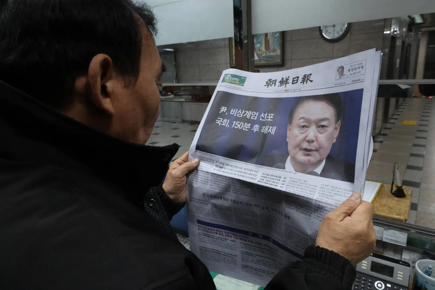 A man looks at a newspaper reporting South Korean President Yoon Suk Yeol announced his intention to lift the emergency martial law in Seoul, South Korea, 04 December 2024. EPA/HAN MYUNG-GU