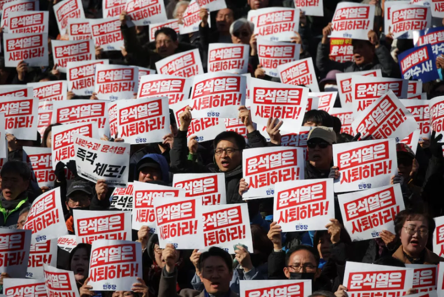 Protesters hold up signs that read "Step down President Yoon Suk Yeol" as people and lawmakers attend a rally in Seoul. REUTERS/Kim Hong-Ji 