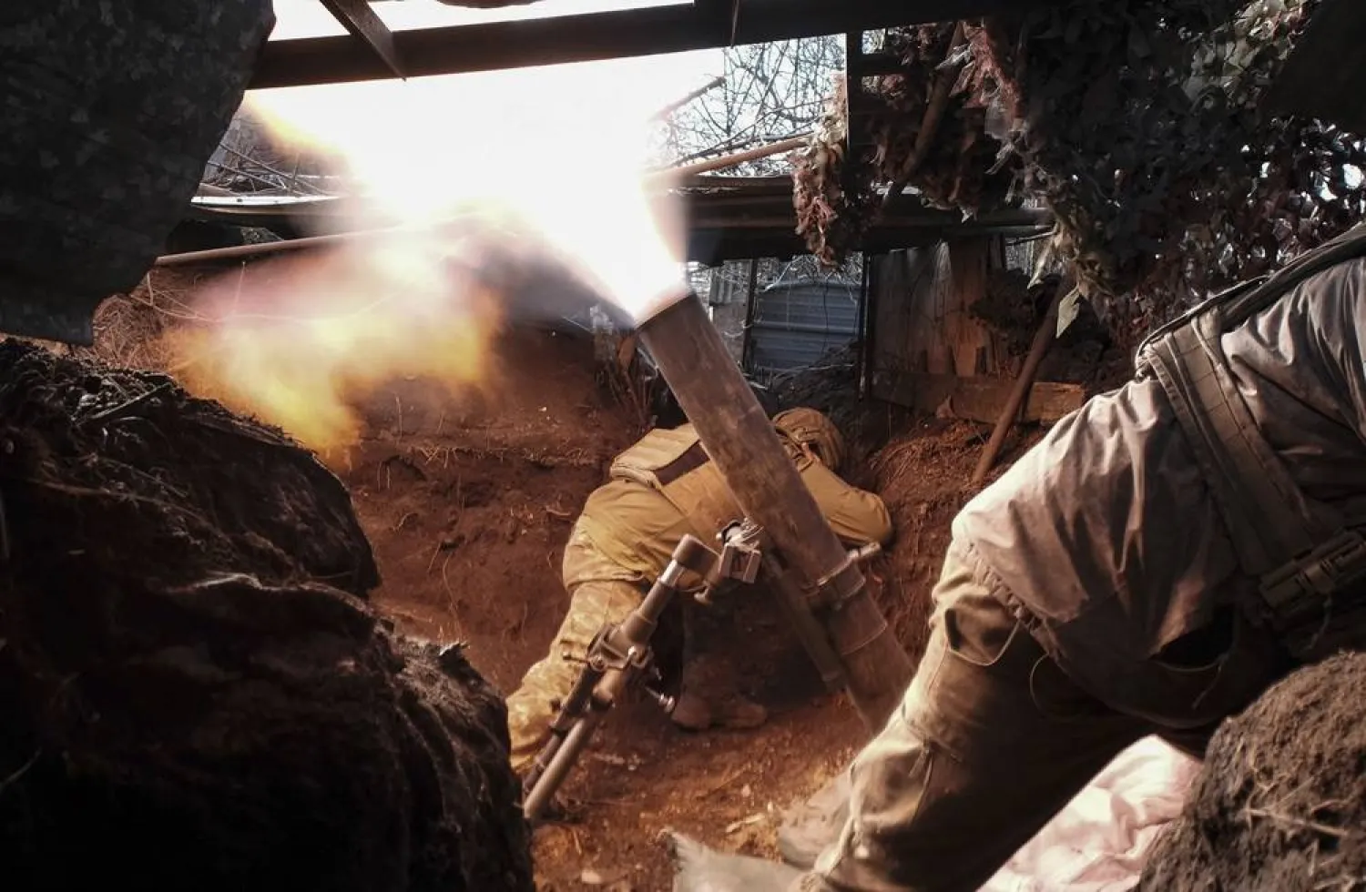 Ukrainian army servicemen of the 47th separate mechanized brigade take cover as they fire a mortar from their position in the Avdiivka direction, at an undisclosed location in the Donetsk area, Ukraine, 24 February 2024, the day of the second anniversary of the Russian invasion. (EPA)