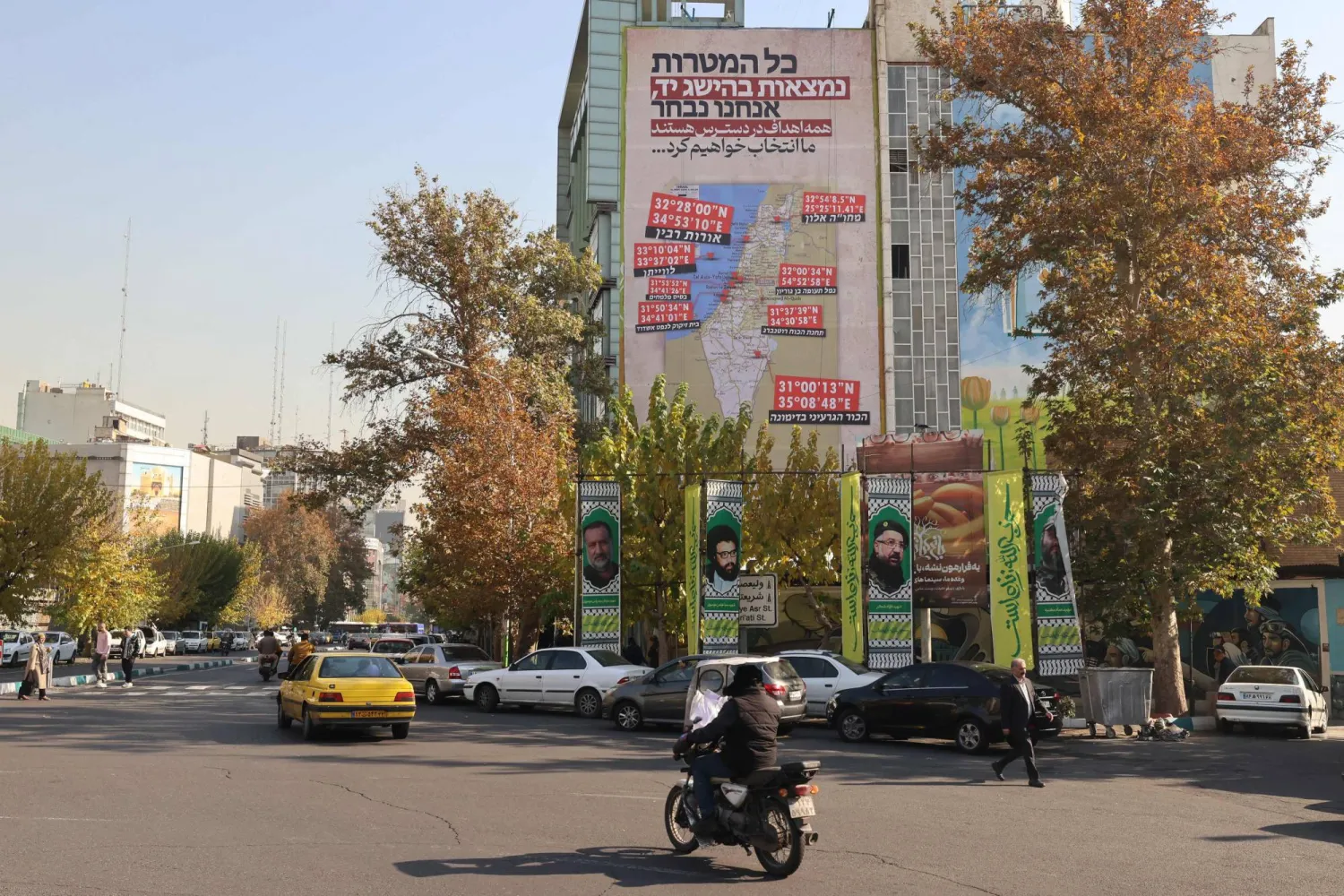 Pedestrians and motorists pass a mural on the facade of a building in Tehran's Palestine Square. (Photo by ATTA KENARE / AFP)