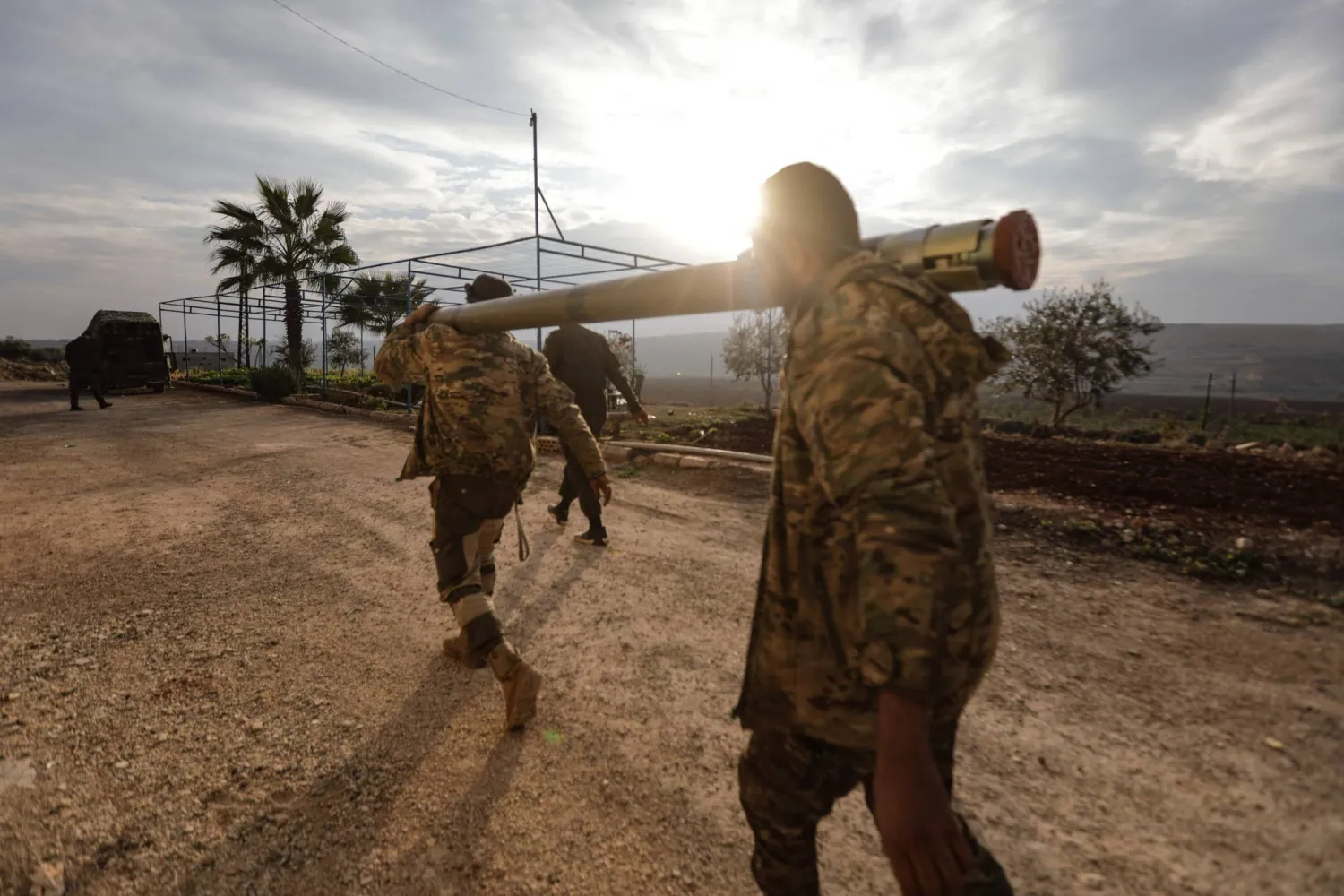 An anti-government fighters carry a rocket to be used against regime forces, in the northern outskirts of Syria's west-central city of Hama on December 4, 2024. (Photo by Bakr AL KASSEM / AFP)
