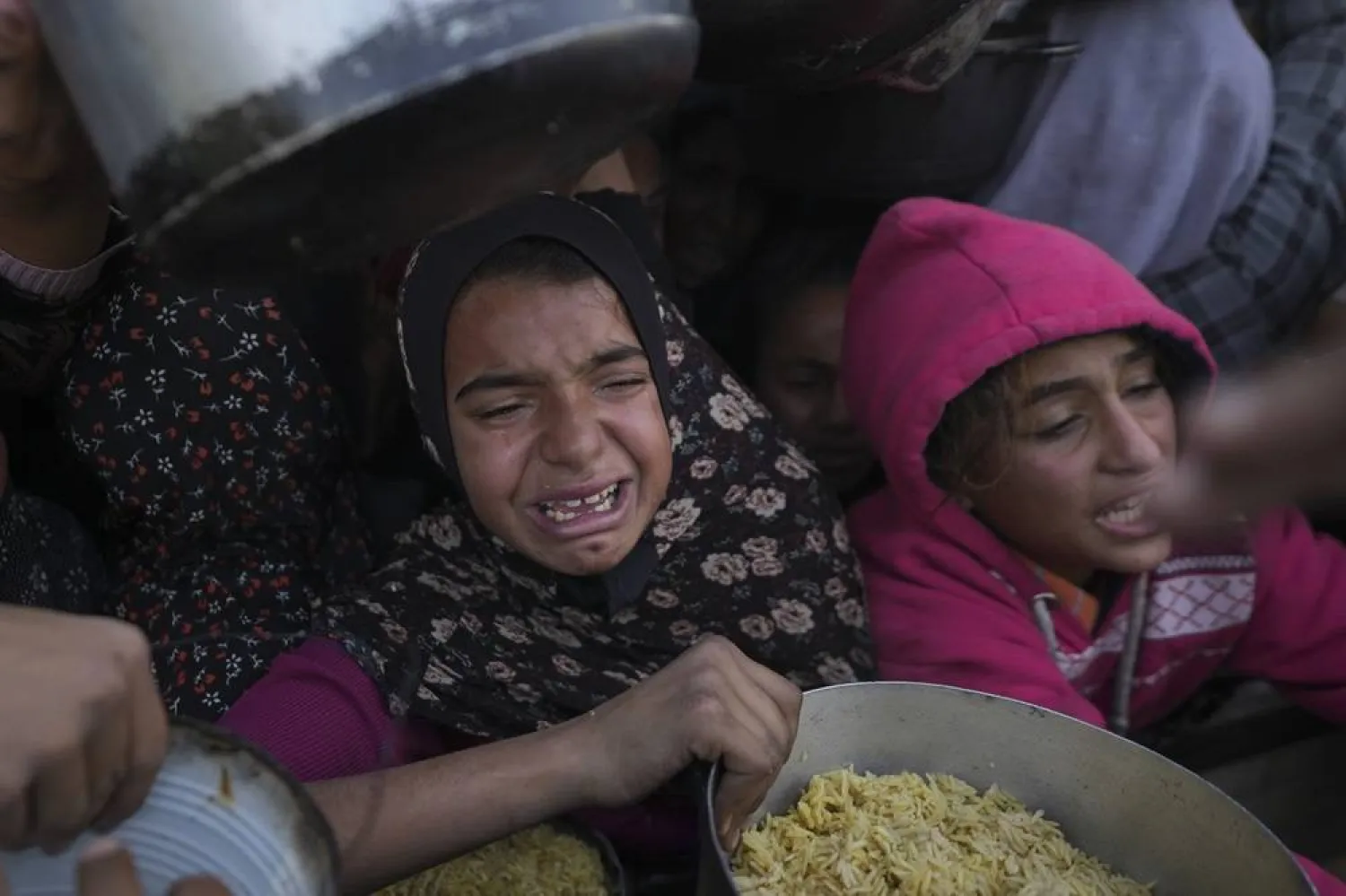  Palestinian girls struggle to reach for food at a distribution center in Khan Younis, Gaza Strip Friday, Dec. 6, 2024. (AP) 