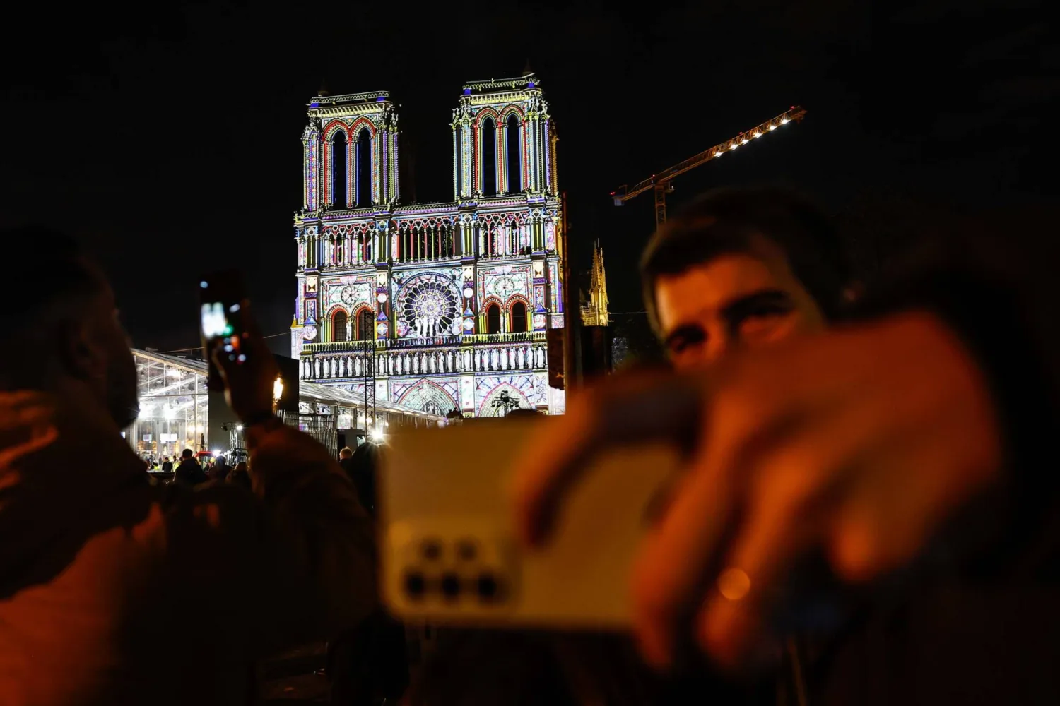 يلتقط الناس صوراً لكاتدرائية نوتردام دو باري خلال الاستعدادات النهائية لإعادة افتتاحها (إ.ب.أ)