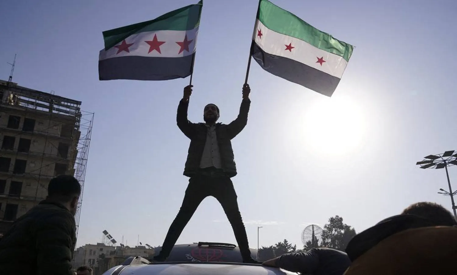 A man holds Syrian opposition flags as he celebrates after Syria's army command notified officers on Sunday that President Bashar al-Assad's 24-year authoritarian rule has ended following a rapid opposition offensive that took the world by surprise, in Aleppo, Syria December 8, 2024. (Reuters) 
