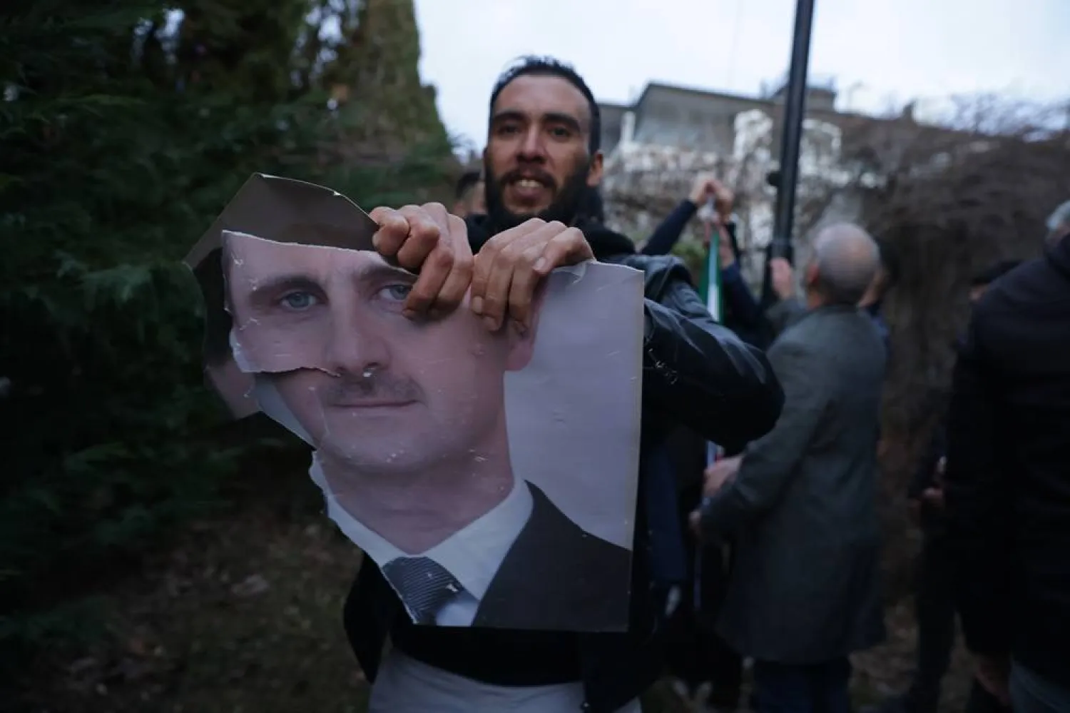 A supporter of the Syrian opposition residing in Serbia tears a portrait of Bashar al-Asad while celebrating the opposition takeover of Damascus at the Syrian embassy in Belgrade, Serbia, 08 December 2024. (EPA) 