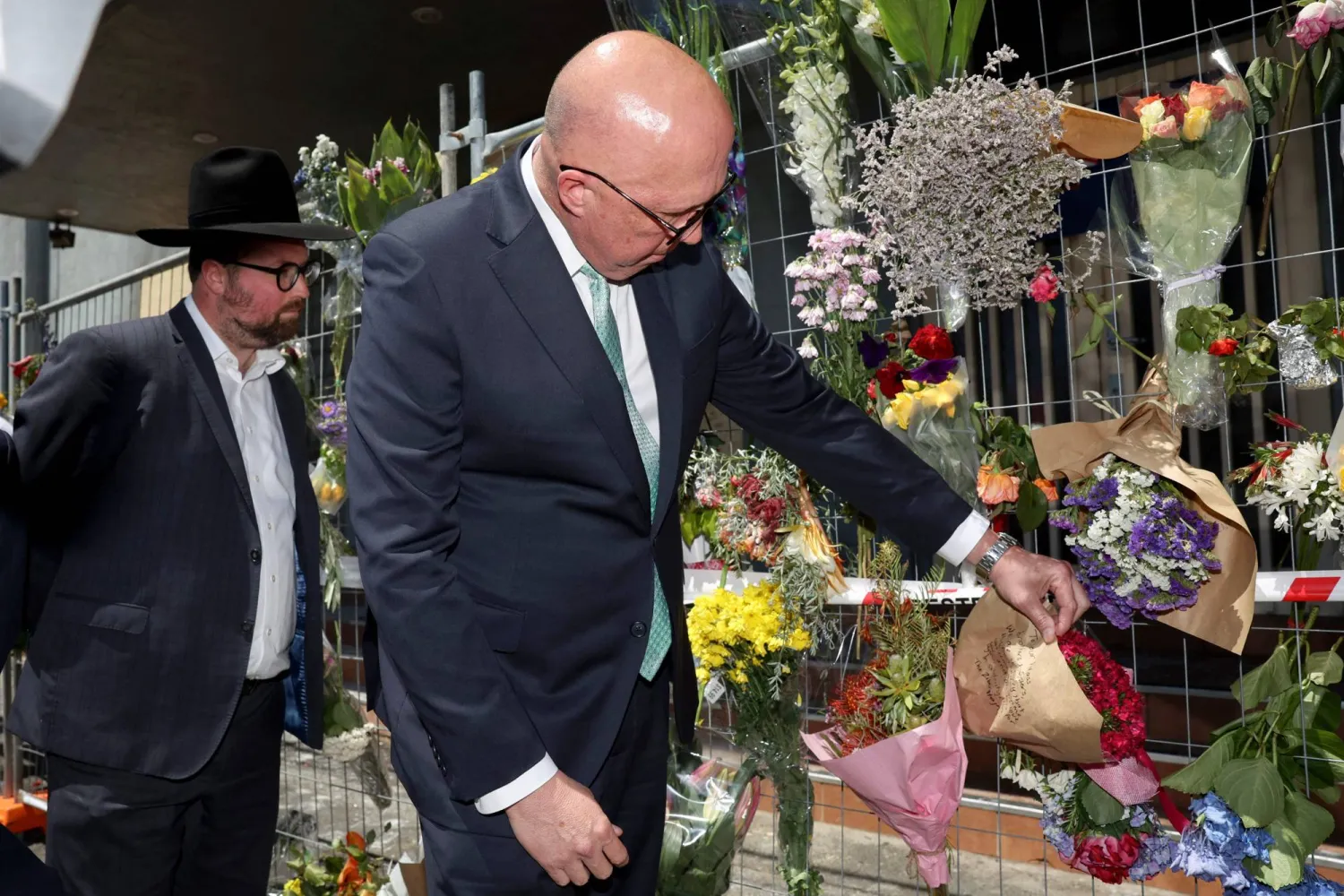 زعيم الحزب الليبرالي الأسترالي بيتر داتون (يمين) ينظر إلى إكليل الزهور الموضوع خارج كنيس «أداس إسرائيل» التالف في ضاحية ريبونليا بملبورن في 9 ديسمبر 2024 (أ.ف.ب)