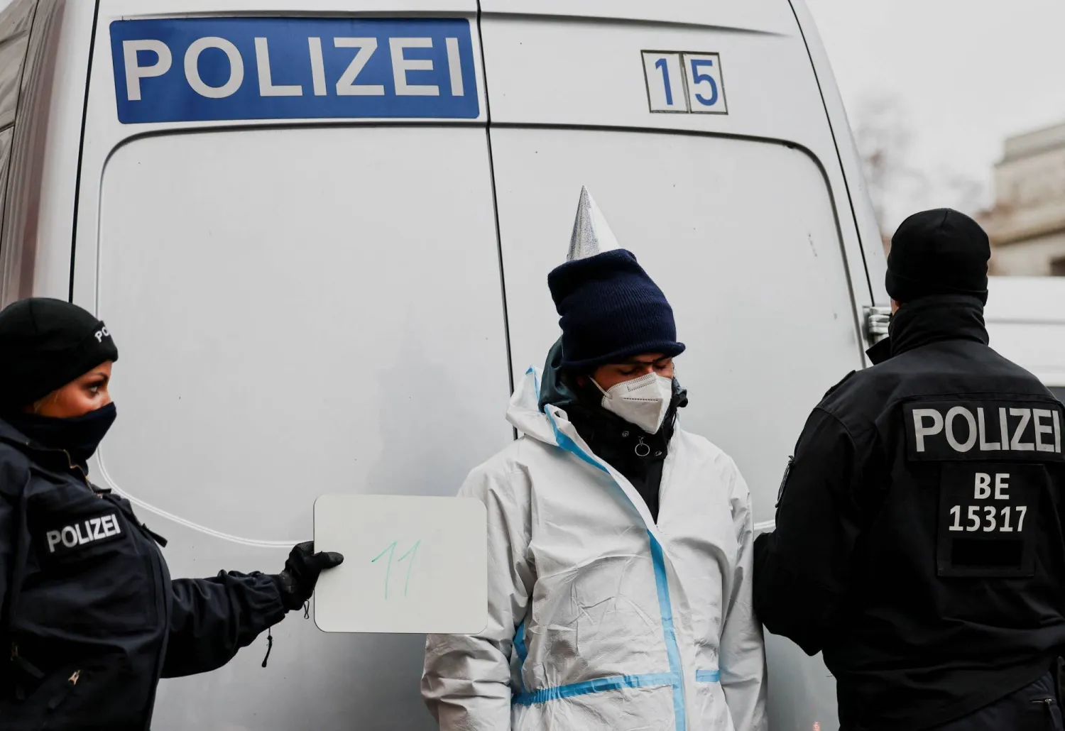 A police officer holds up a whiteboard with a number as a protester from the activist group "Ende Gelaende" is photographed after being detained by the police during a protest against the World LNG Summit, near the Hotel Adlon in Berlin, Germany, December 10, 2024. REUTERS/Christian Mang