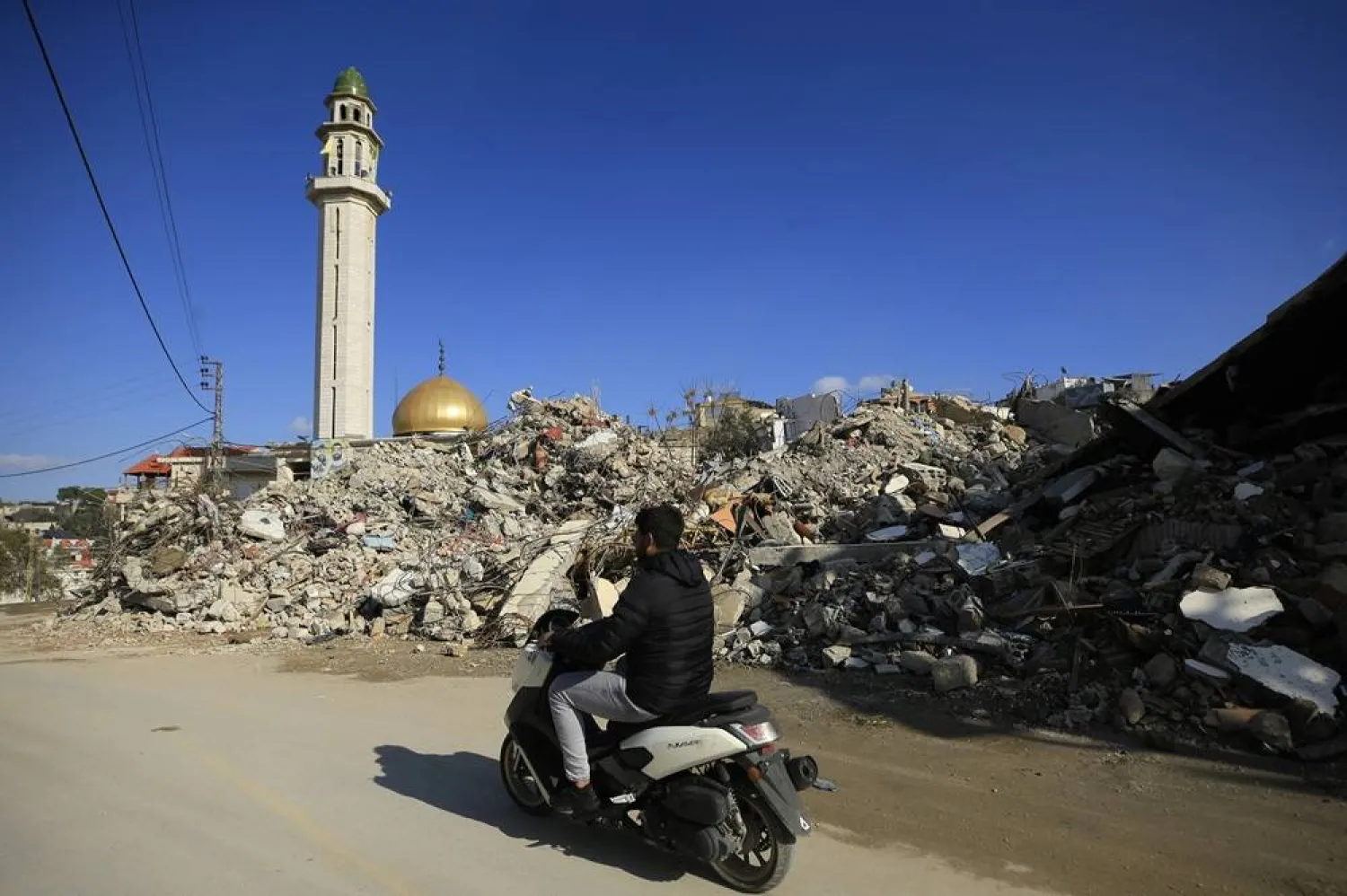 People ride past damaged buildings, following a ceasefire deal between Israel and Hezbollah, at Baraashit in the Bint Jbeil district of southern Lebanon, 05 December 2024. (EPA)