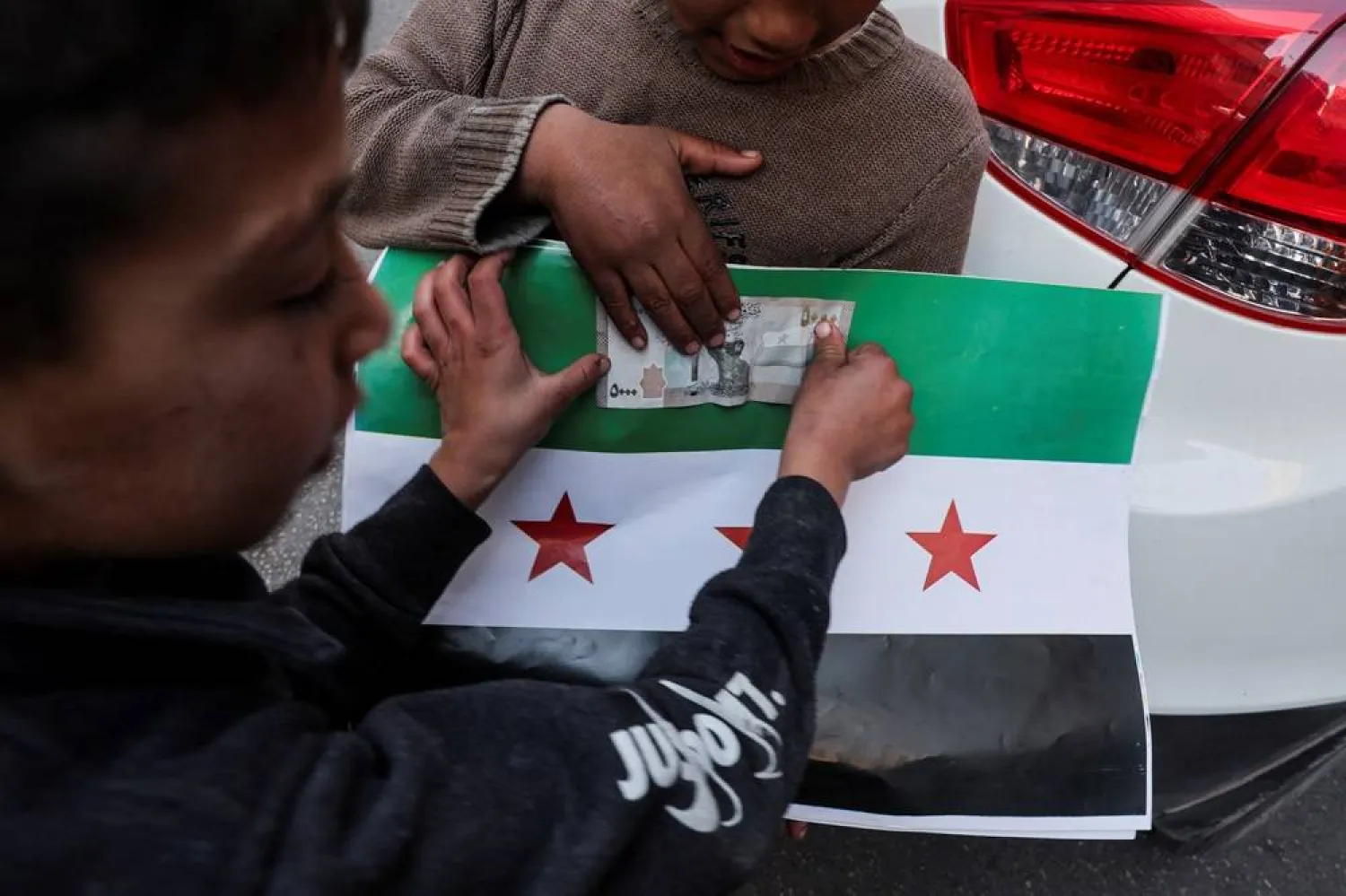  A boy sells pictures of the flag adopted by the new Syrian rulers, after the ousting of Syria's Bashar al-Assad, in Damascus, Syria, December 16, 2024. (Reuters)