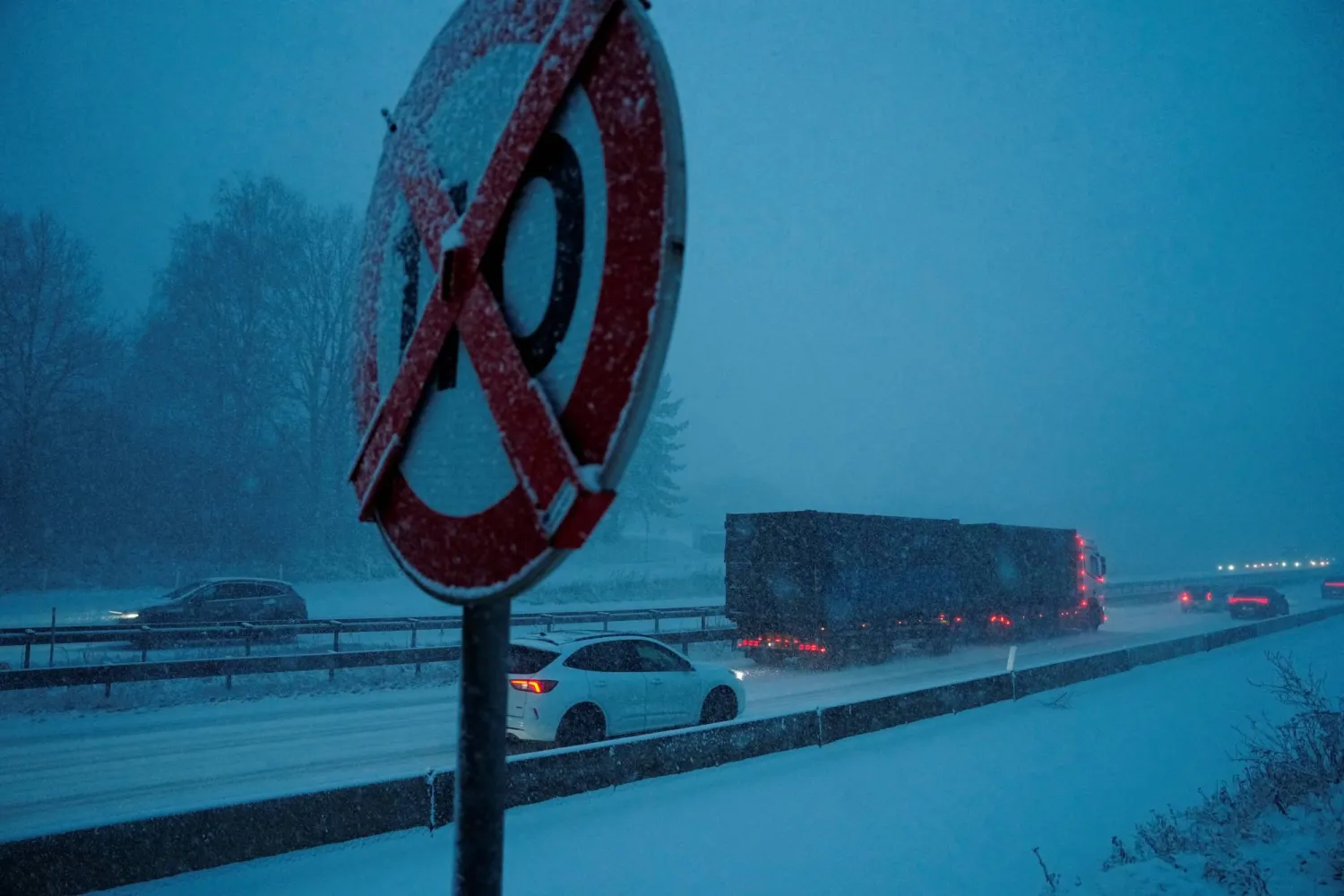 علامة حد السرعة تغطيها الثلوج فيما تتحرك المركبات على طول الطريق السريع وسط ثلوج كثيفة بالقرب من لوندتوفتي شمال كوبنهاغن بالدنمارك (رويترز)