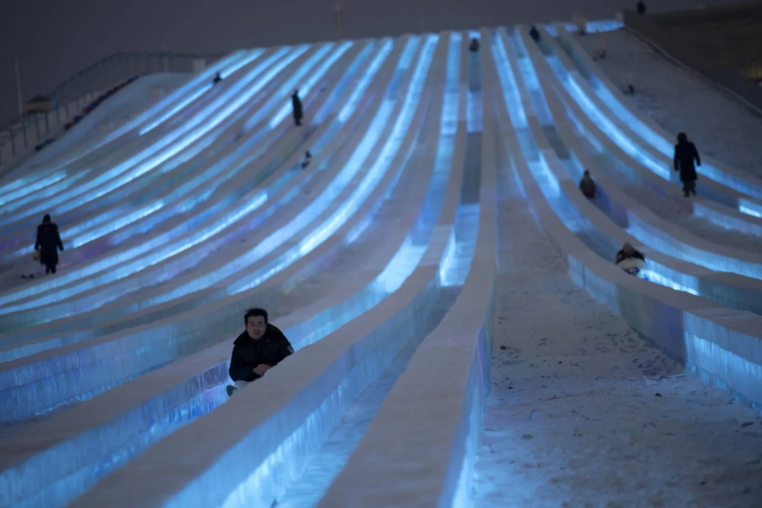 يتزلج الزوار على الجليد بأحد الهياكل الجليدية بمهرجان هاربين للجليد والثلج في مقاطعة هيلونغجيانغ بالصين (إ.ب.أ)