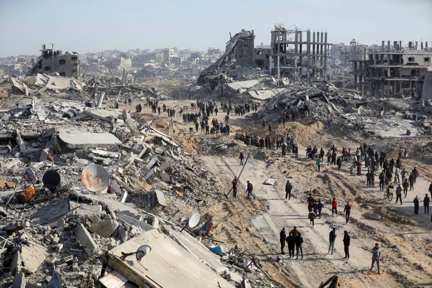 نازحون فلسطينيون يسيرون وسط منازلهم المدمرة في شمال قطاع غزة (رويترز)